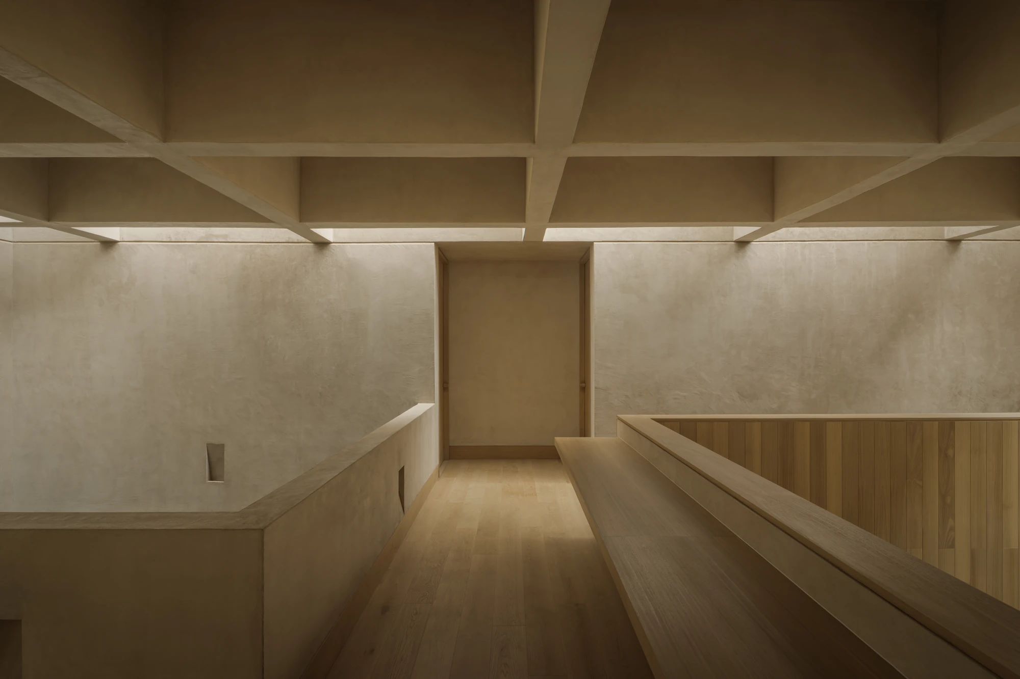 Casa Azaleas by V Taller, photographed by Funciono — The bridge level, a long oak bench running beside a plaster parapet under a ribbed ceiling lit from perimeter skylights.
