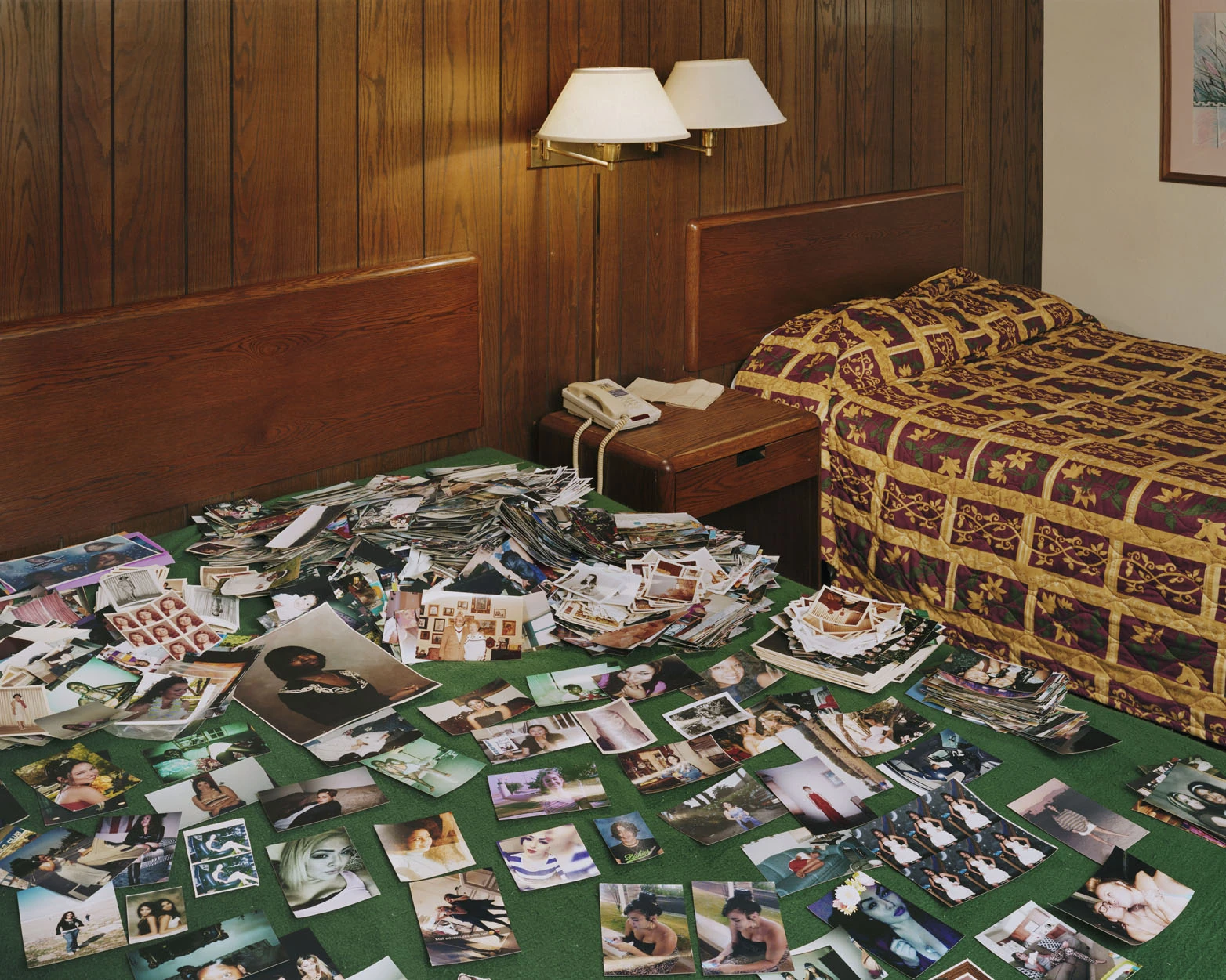 A Pound of Pictures by Alec Soth, photographed by Alec Soth — Studio portraits spread across the green carpet of a wood-panelled motel room beside a floral bedspread, from A Pound of Pictures by Alec Soth.