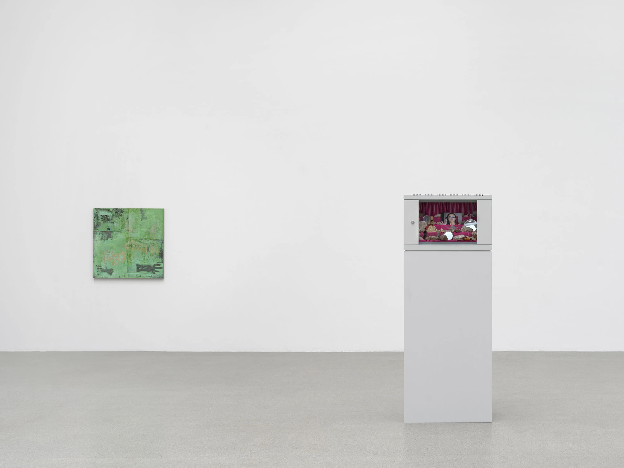 Dolls' Theater by Mimosa Echard, photographed by Julien Gremaud, Annik Wetter — A small green tableau faces a grey rack cabinet on a tall plinth, its interior lined in magenta velvet and packed with pale limestone.