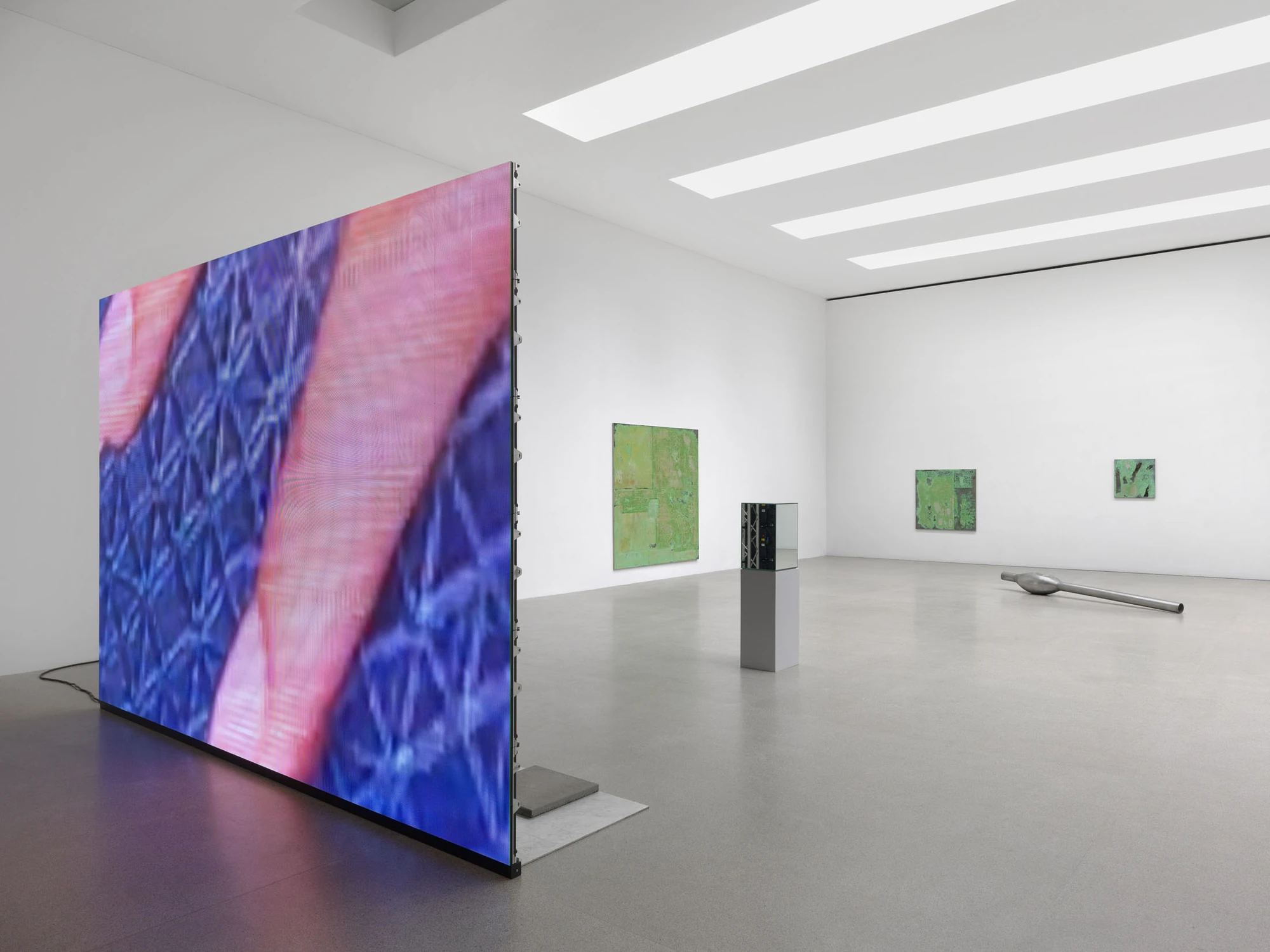 Dolls' Theater by Mimosa Echard, photographed by Julien Gremaud, Annik Wetter — The LED wall seen from the front at full height, pink bands crossing a blue lattice, with green tableaux and a plinth vitrine beyond.