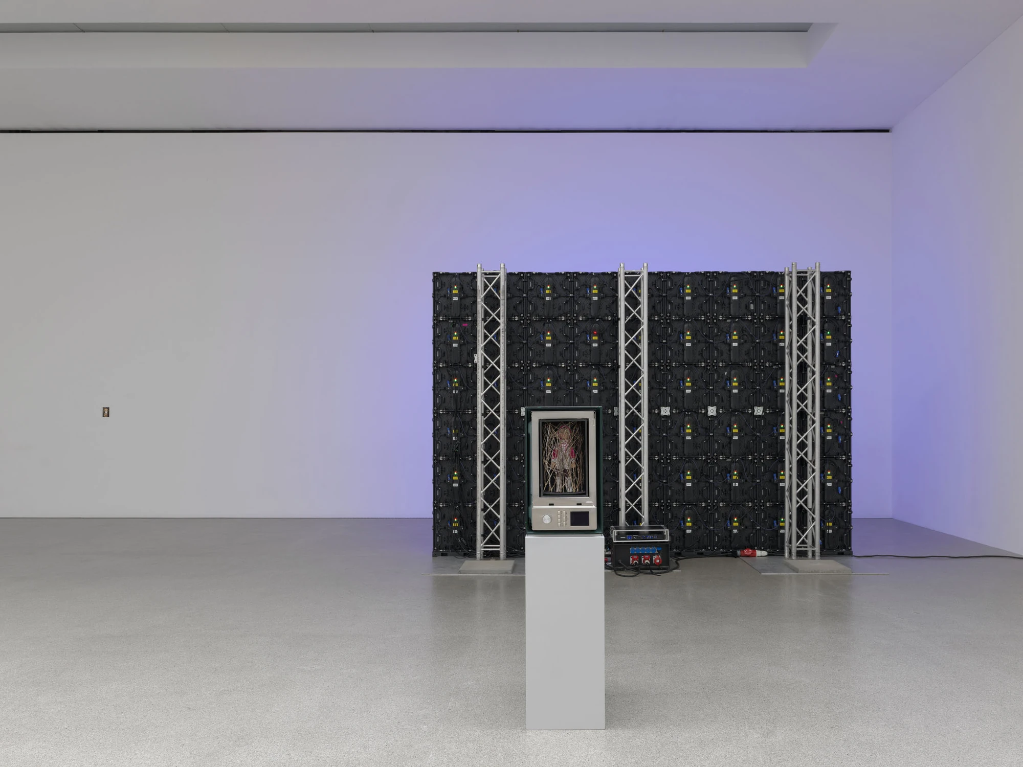 Dolls' Theater by Mimosa Echard, photographed by Julien Gremaud, Annik Wetter — The rear of the LED wall: black panel modules with coloured status lights on aluminium truss, a microwave on a plinth in front, lavender light washing the wall.