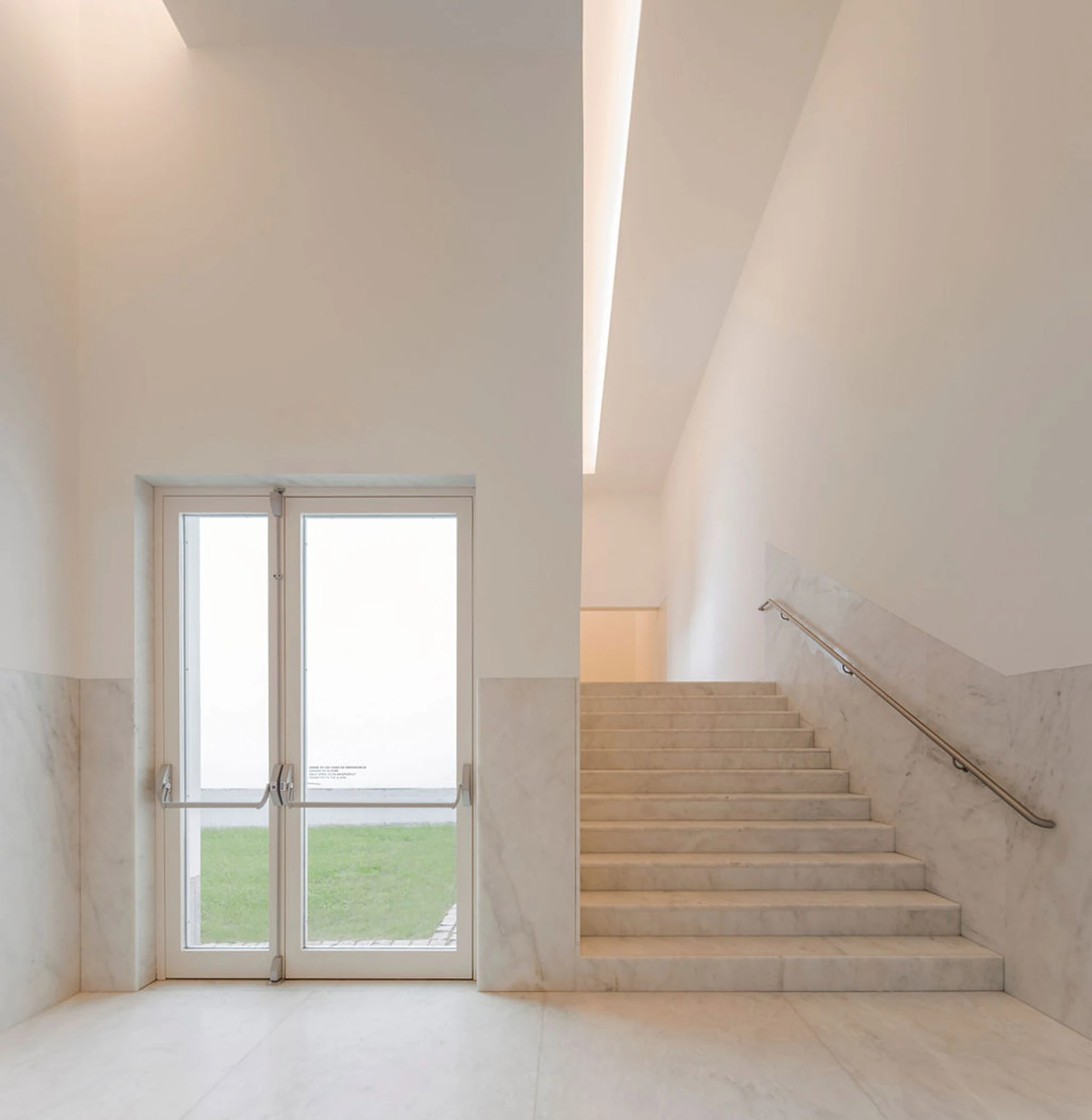 Serralves Museum New Wing by Álvaro Siza — Marble stair and marble-lined walls at the entrance of the Álvaro Siza Wing, next to a glazed door opening onto grass.