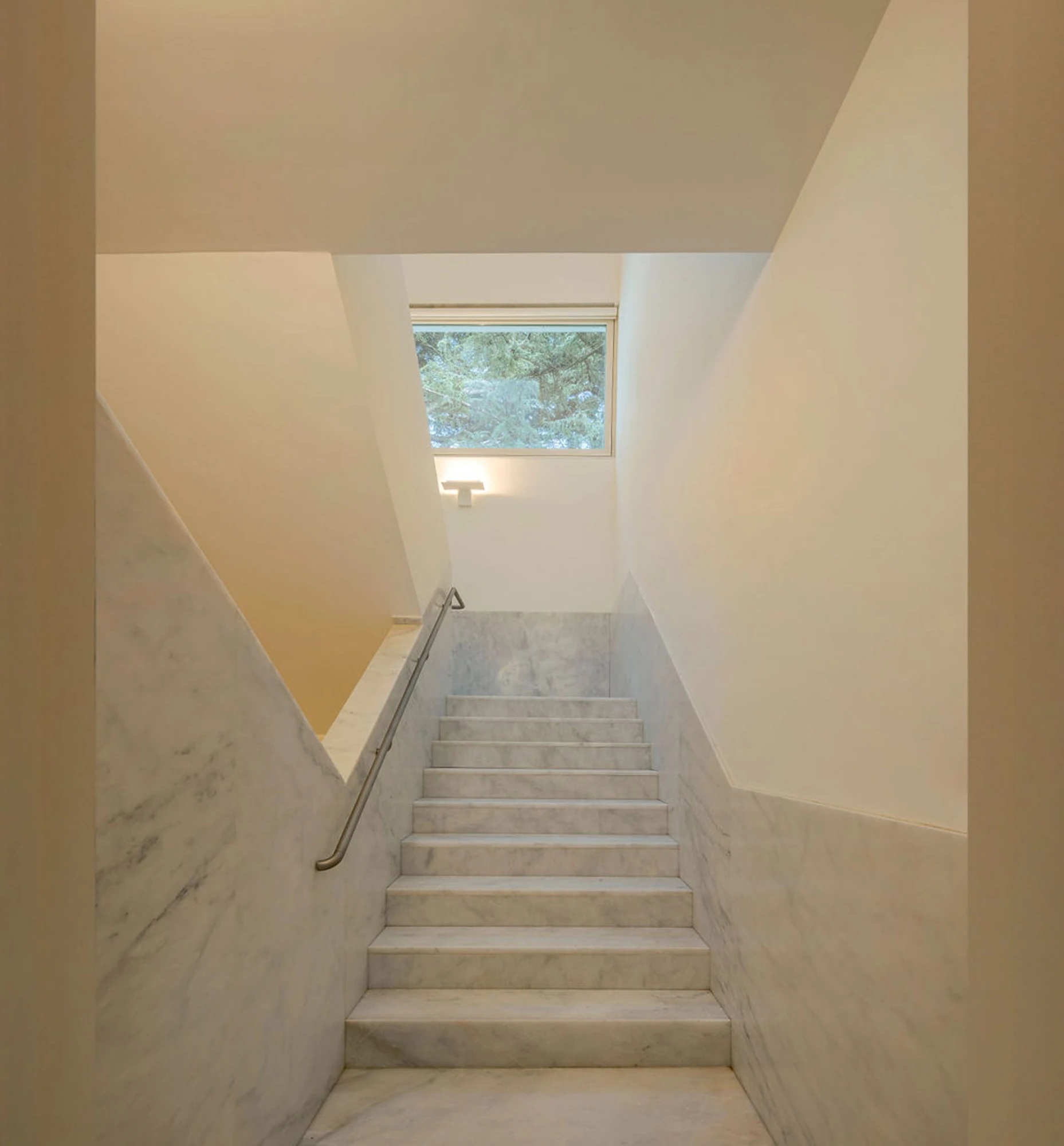 Serralves Museum New Wing by Álvaro Siza — Marble stair rising toward a square window filled with pine branches inside the Álvaro Siza Wing.