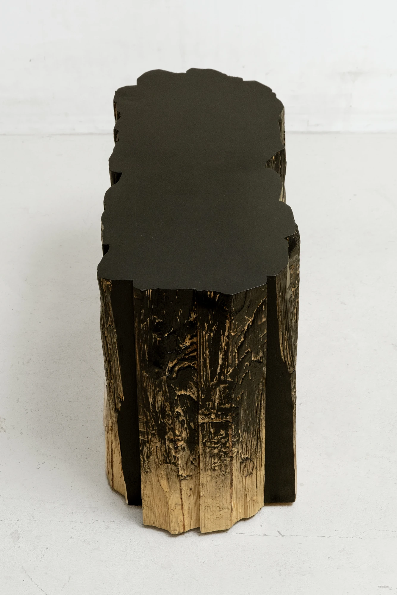 In Between Wood and Fire by Didi NG Wing Yin, photographed by Didi NG Wing Yin — Pith Stool B seen end on from above, the black seat plane reading as one shape against the fluted split sides below it.