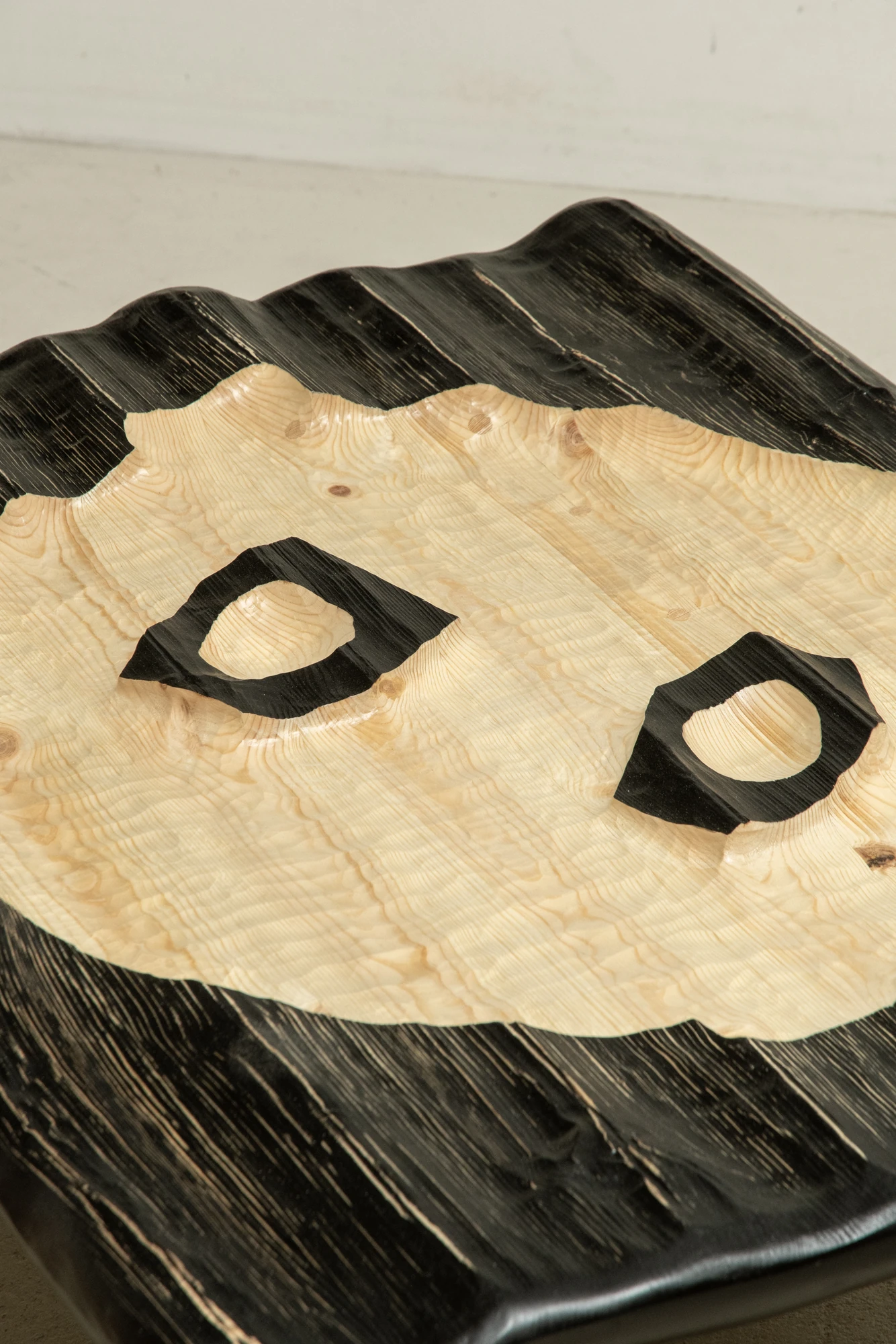 In Between Wood and Fire by Didi NG Wing Yin, photographed by Didi NG Wing Yin — Close view of the Rocket Side Coffee Table top, where the blackened combed surface gives way to bare pale wood around two apertures rimmed in char.