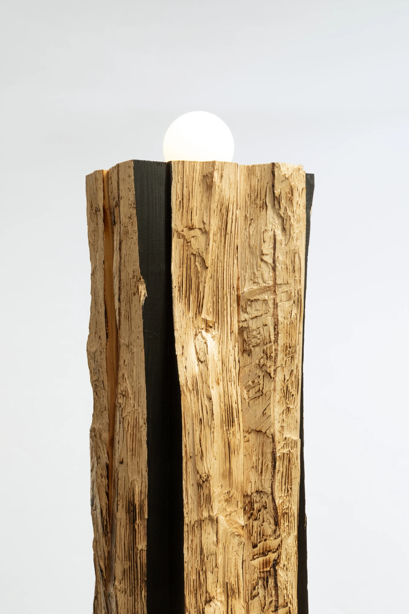 In Between Wood and Fire by Didi NG Wing Yin, photographed by Didi NG Wing Yin — Upper section of the Pith Floor Lamp, the opal globe seated in the notch where the split through the beam opens out.