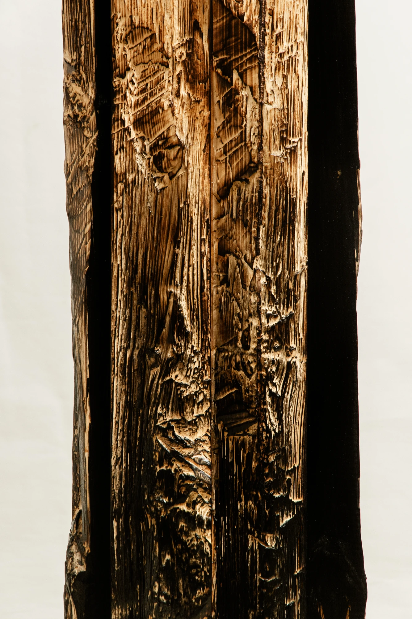 In Between Wood and Fire by Didi NG Wing Yin, photographed by Didi NG Wing Yin — Surface detail of the Pith Floor Lamp, carved facets and torn grain running the height of the split face.