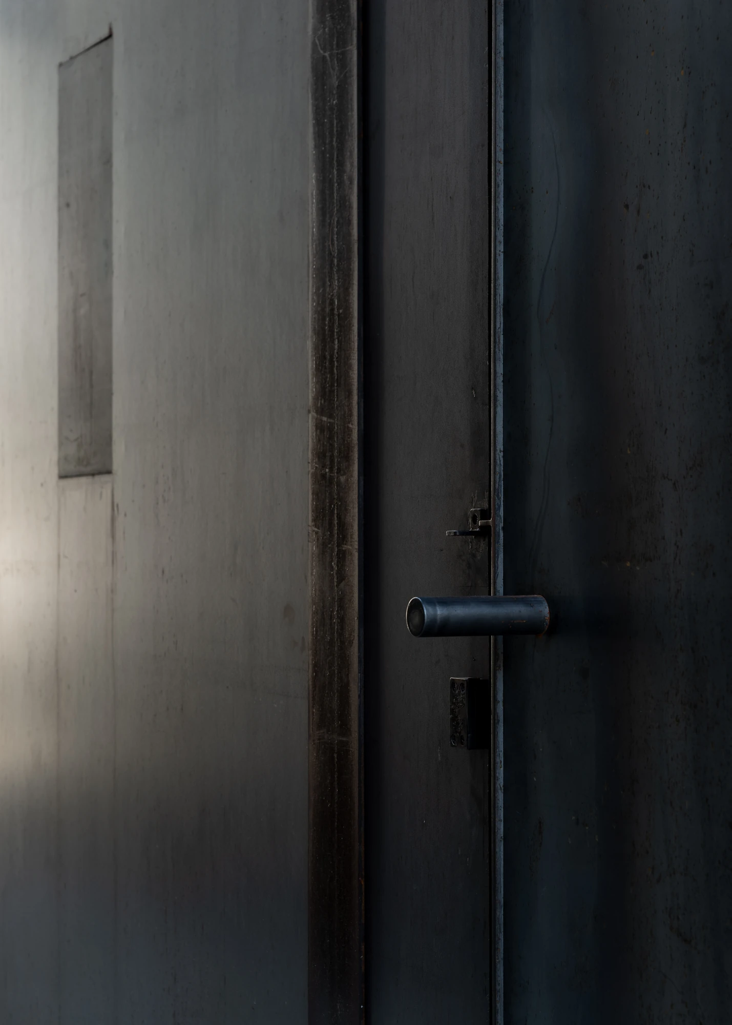 Shironishi Office by Tomoaki Uno Architects, photographed by Nathanael Bennett — Grazing light on the open door edge, a turned steel bar handle and its keeper.