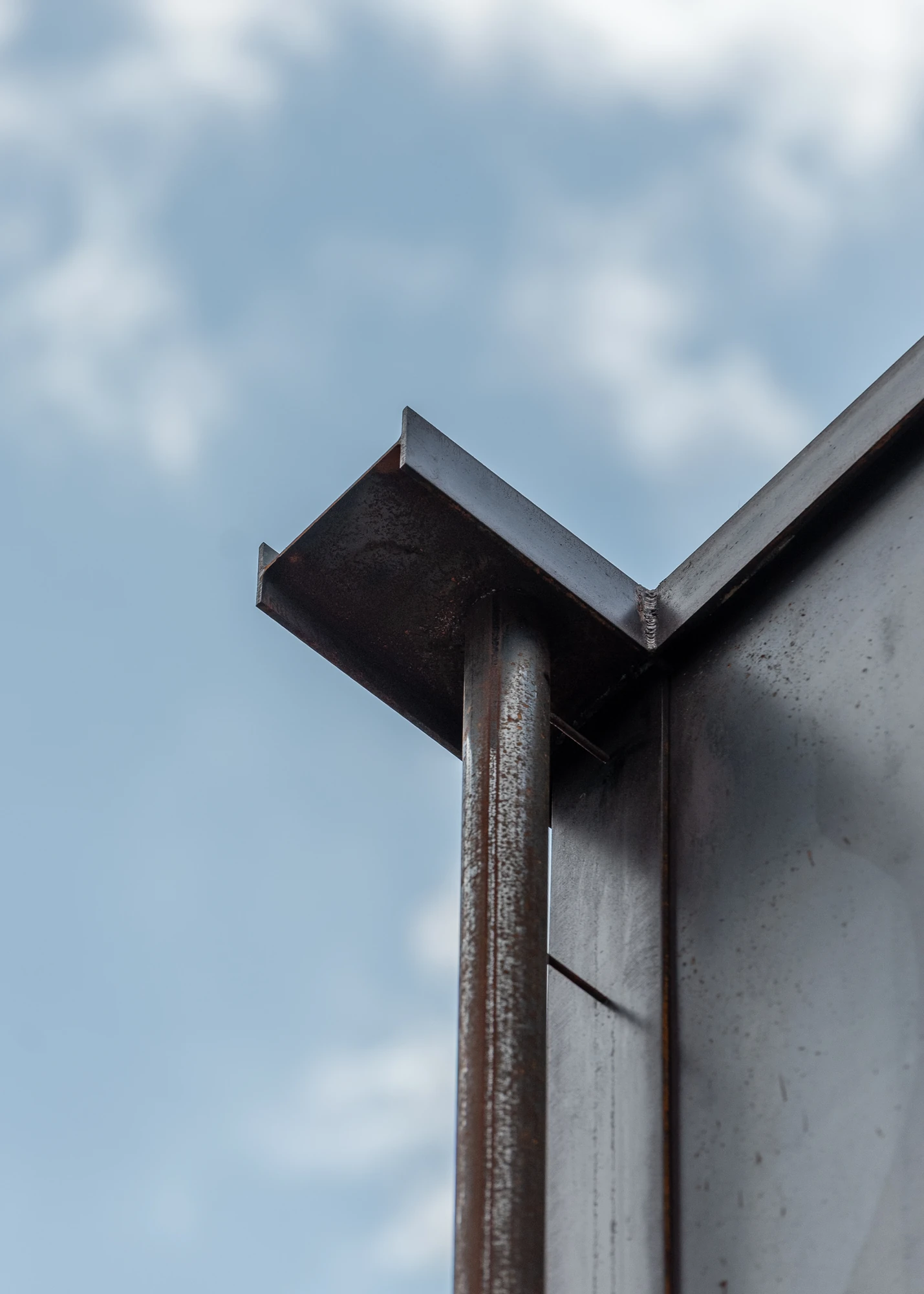 Shironishi Office by Tomoaki Uno Architects, photographed by Nathanael Bennett — Looking up at the parapet, a folded steel angle capping the wall beside a round downpipe against cloud.