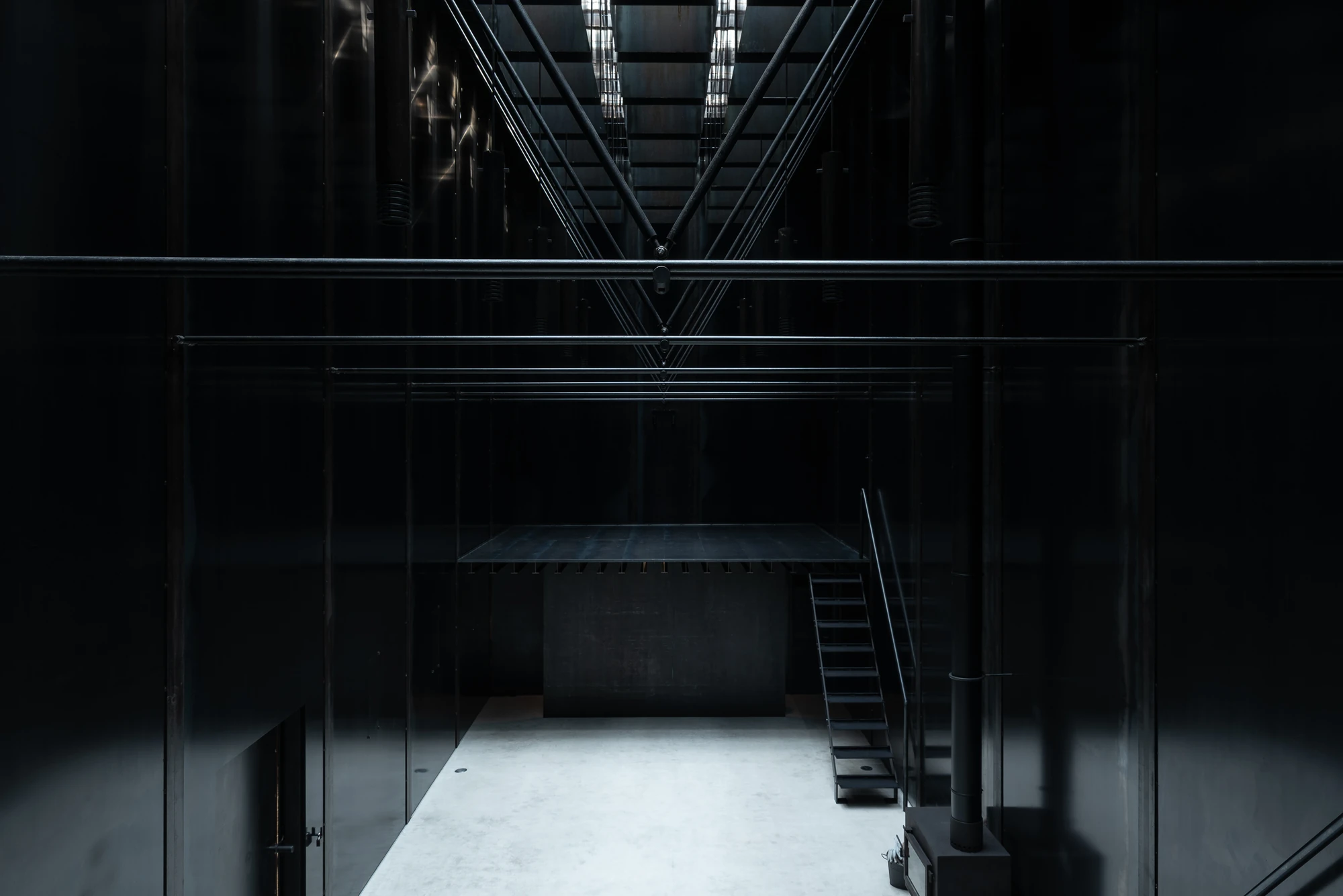 Shironishi Office by Tomoaki Uno Architects, photographed by Nathanael Bennett — Wide view of the interior with tension rods crossing overhead and the skylight slots dropping a band of light onto the floor.