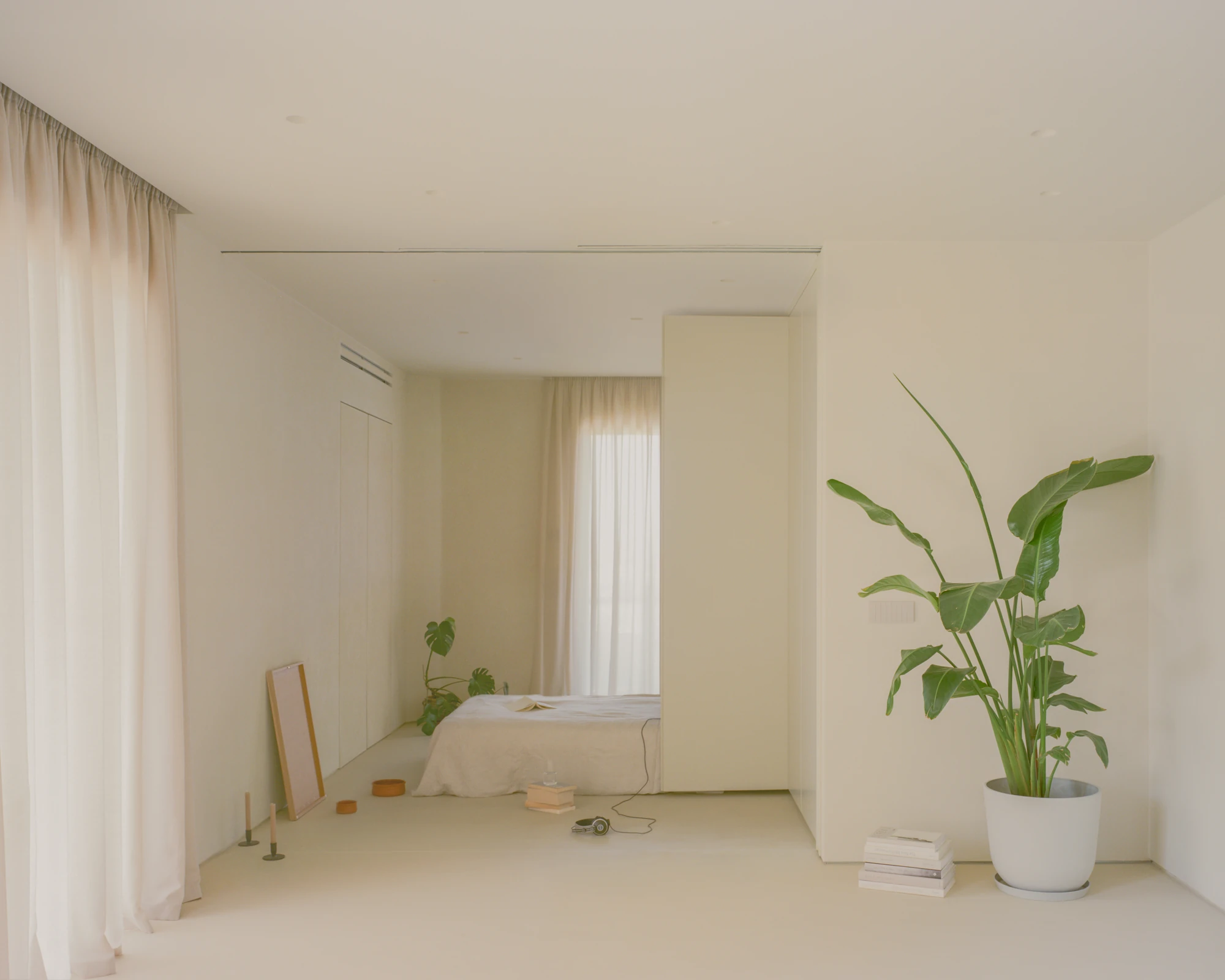 Kifisia Apartment by Georgios Apostolopoulos Architects, photographed by Lorenzo Zandri — The same far end with the bed folded down, bedding loose on the floor and the sliding panel pushed across.