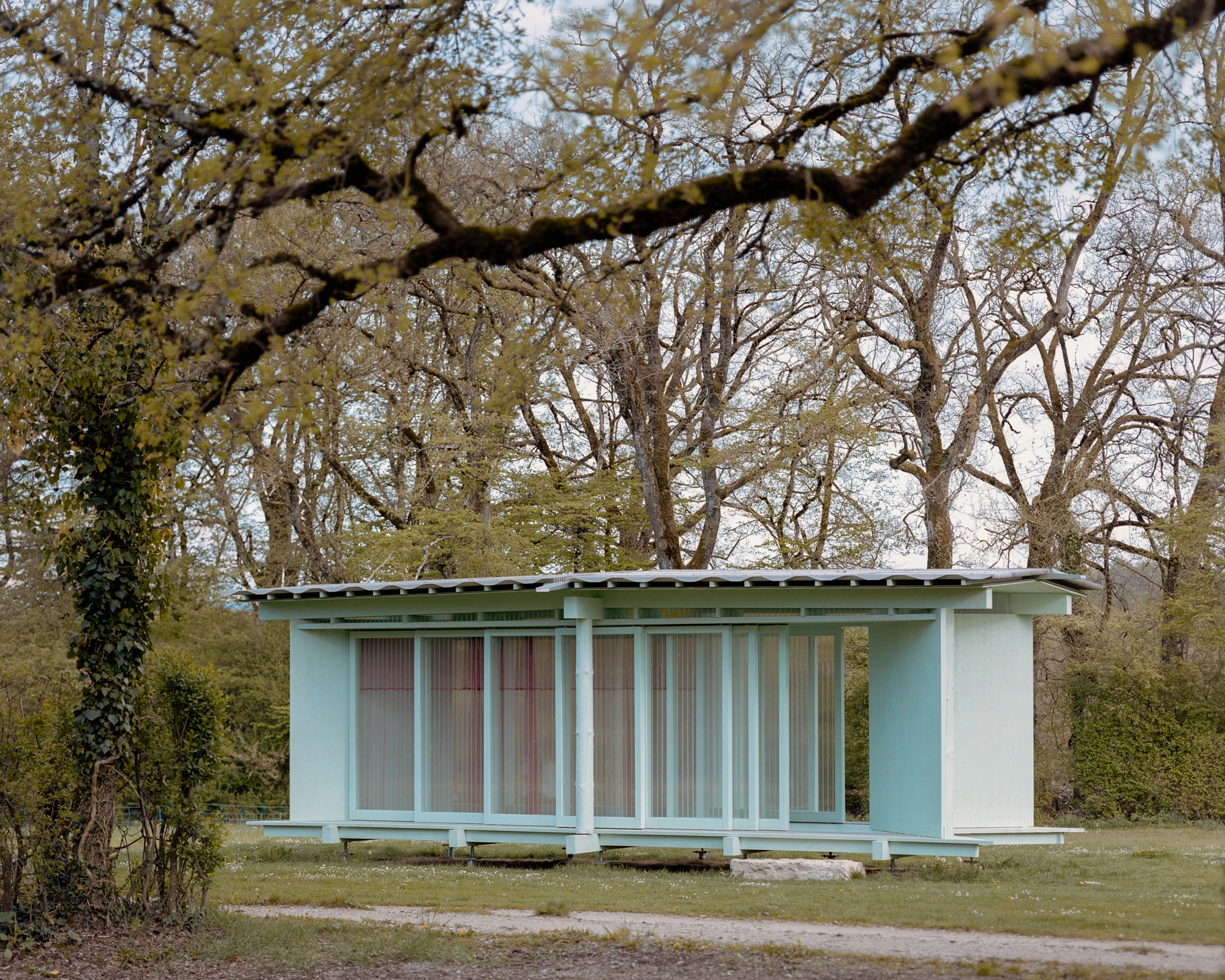 Pavilion of the Sliding Doors by Piertzovanis Toews, photographed by Federico Farinatti — Frontal view of the long elevation under bare oaks.