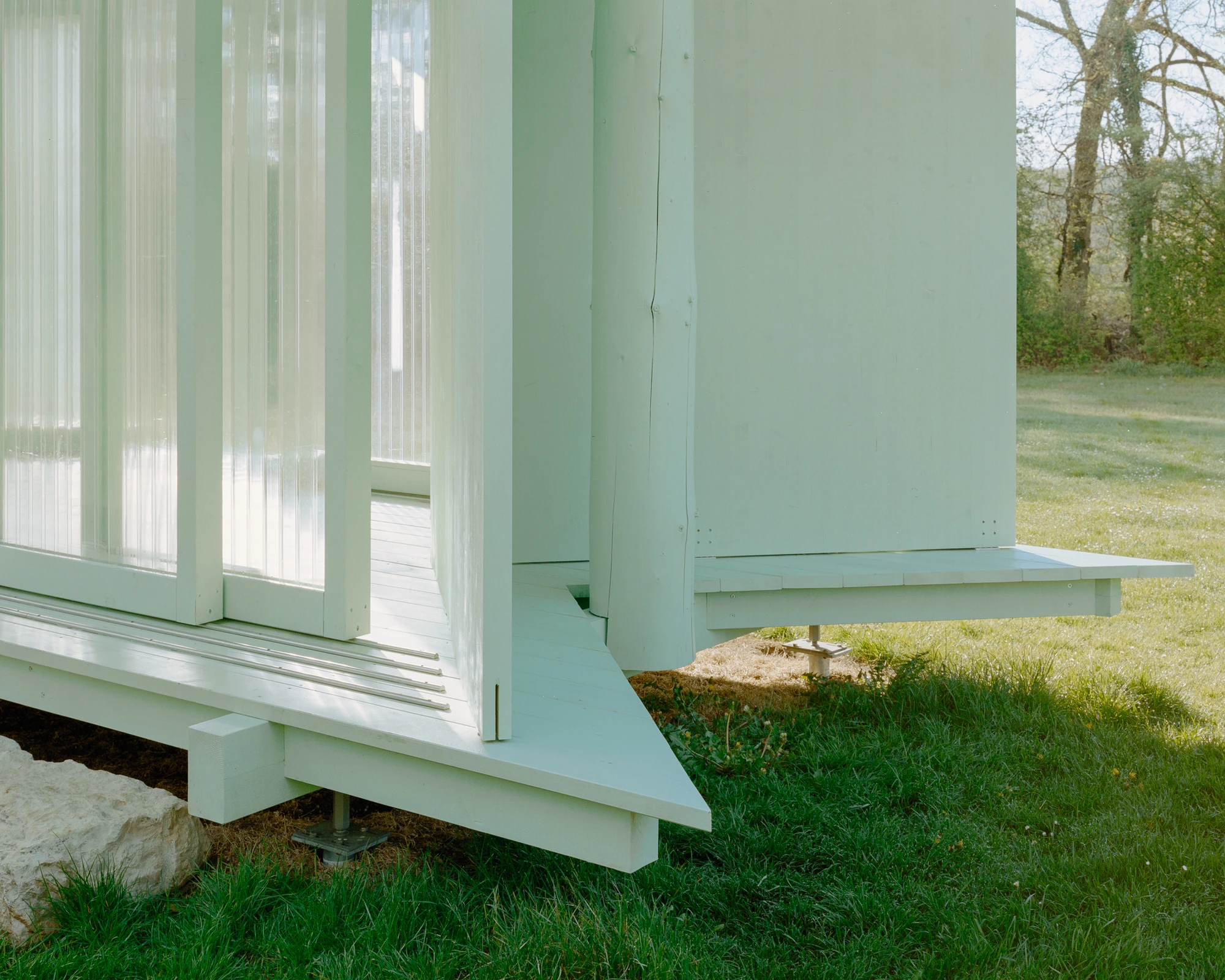 Pavilion of the Sliding Doors by Piertzovanis Toews, photographed by Federico Farinatti — A detail of the deck edge where a painted timber ramp meets the platform.