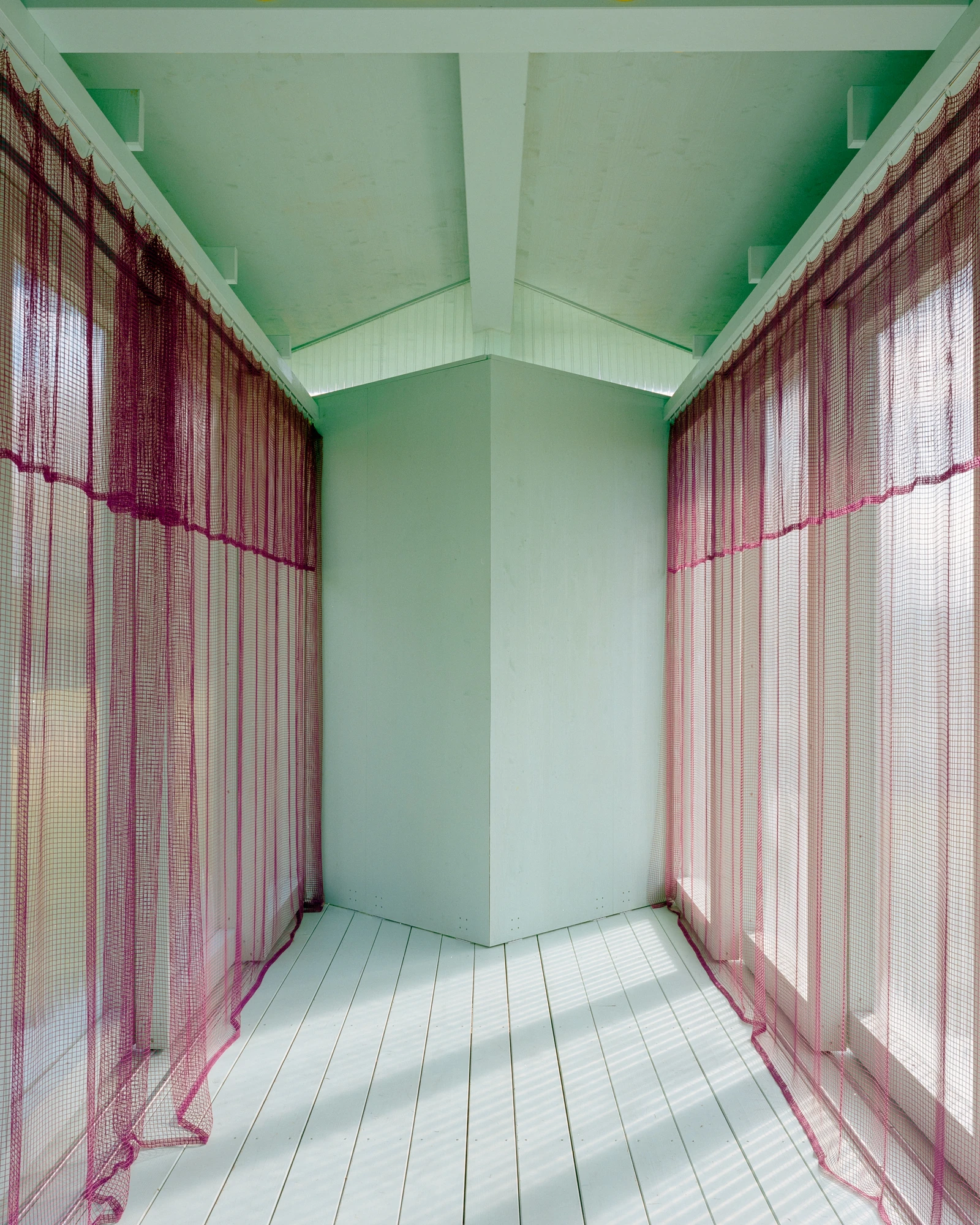 Pavilion of the Sliding Doors by Piertzovanis Toews, photographed by Federico Farinatti — Pink mesh curtains hang the full height along both sides of the interior, gathered against the panels.