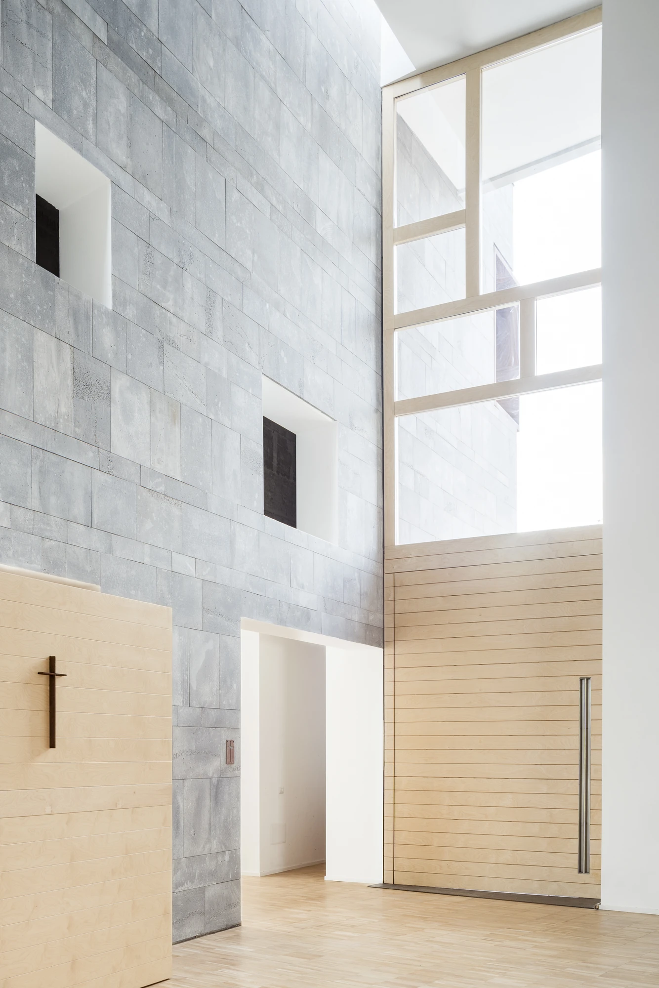 Complesso parrocchiale e Chiesa della Beata Vergine Assunta by Carlo Atzeni, Silvia Mocci, Maurizio Manias, Franceschino Serra, photographed by Studio Vetroblu — Square openings are punched through the double height basalt wall at irregular heights.