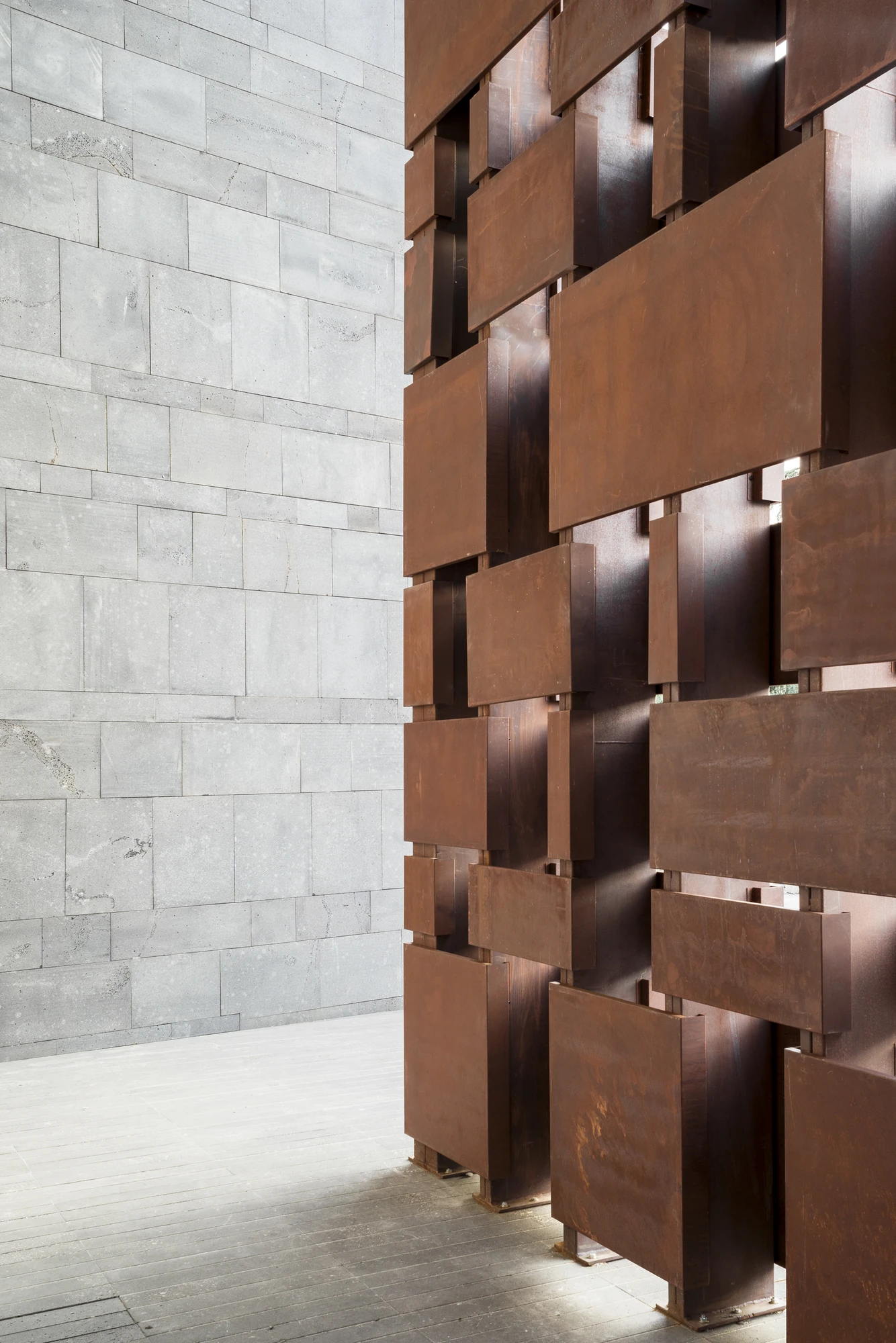 Complesso parrocchiale e Chiesa della Beata Vergine Assunta by Carlo Atzeni, Silvia Mocci, Maurizio Manias, Franceschino Serra, photographed by Studio Vetroblu — The corten screen seen edge on, its plates staggered forward and back so light catches each…