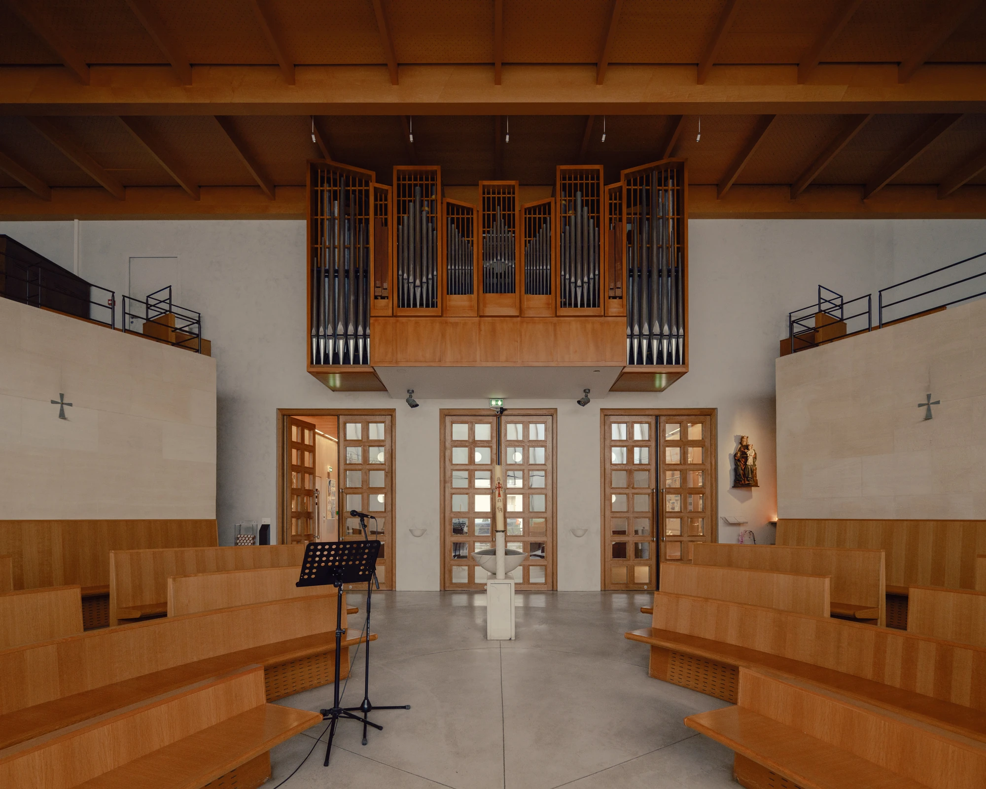 Église Saint-François de Molitor by Corinne Callies and Jean-Marie Duthilleul — The organ sits in timber casework on the gallery above three sets of glazed timber doors, its pipes ranked behind slim vertical framing.