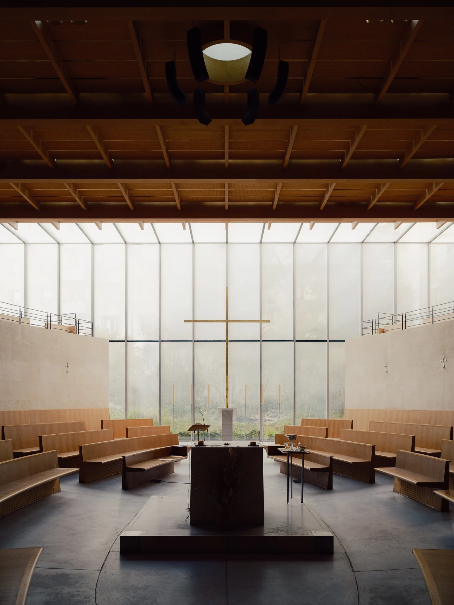 Église Saint-François de Molitor by Corinne Callies and Jean-Marie Duthilleul — A centred view down onto the altar, a single dark stone monolith on a stepped platform, with the brass cross aligned directly above and behind it.