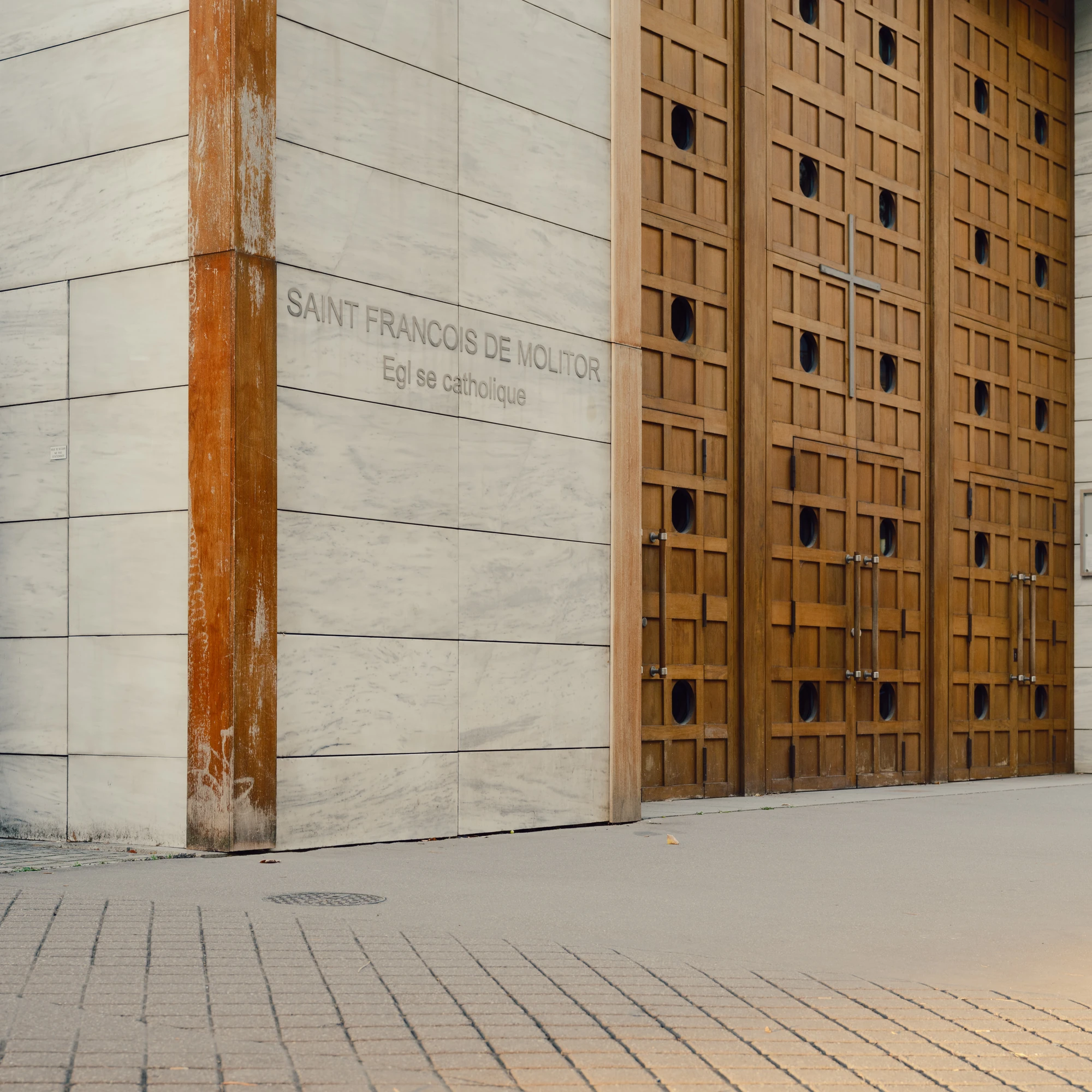 Église Saint-François de Molitor by Corinne Callies and Jean-Marie Duthilleul — The street corner of the church, its marble cladding engraved with the name of the parish above the line reading Église catholique.