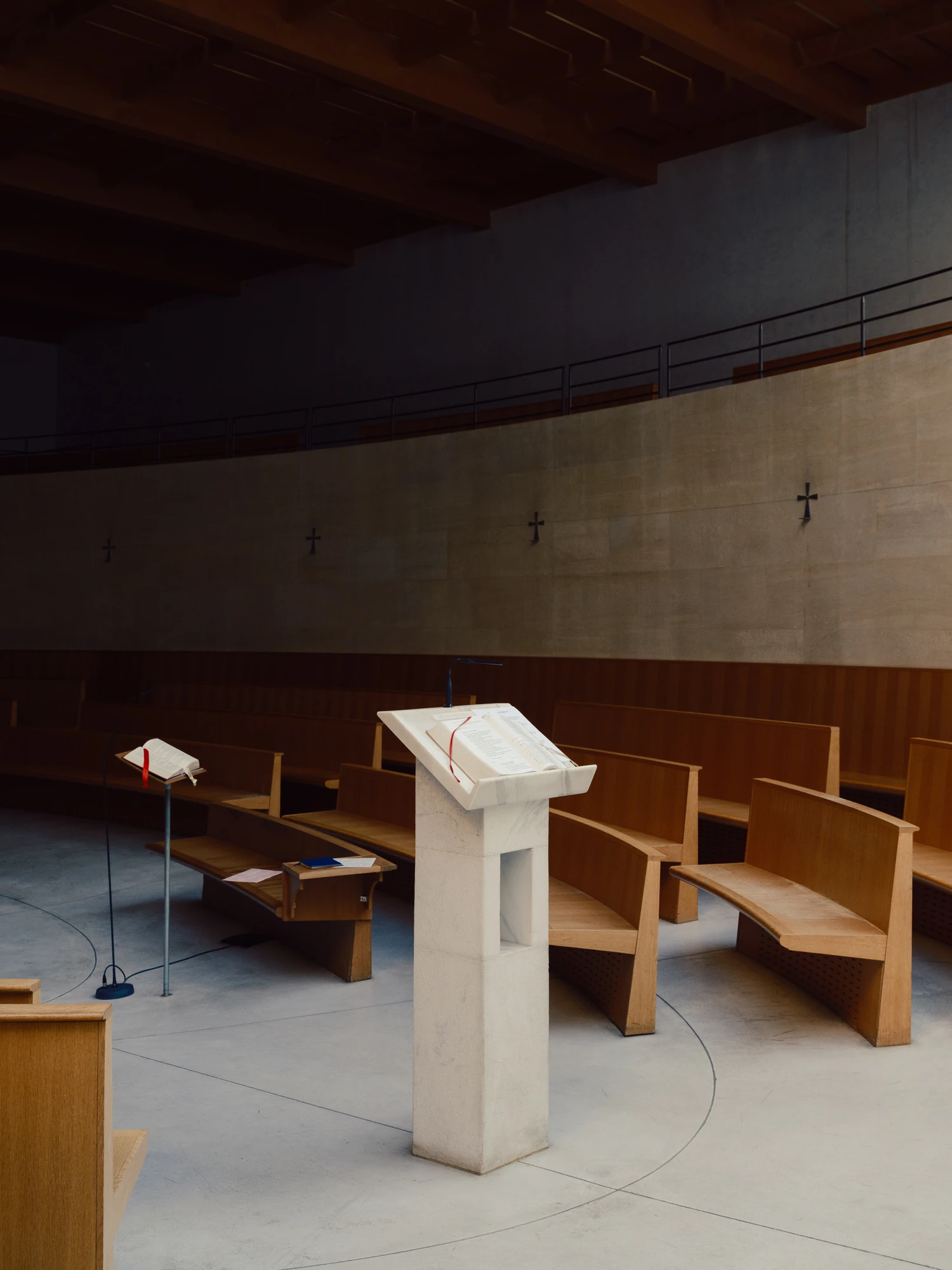 Église Saint-François de Molitor by Corinne Callies and Jean-Marie Duthilleul — The pale stone ambo with an open book laid on it, standing on the polished floor inside the curve of the benches.
