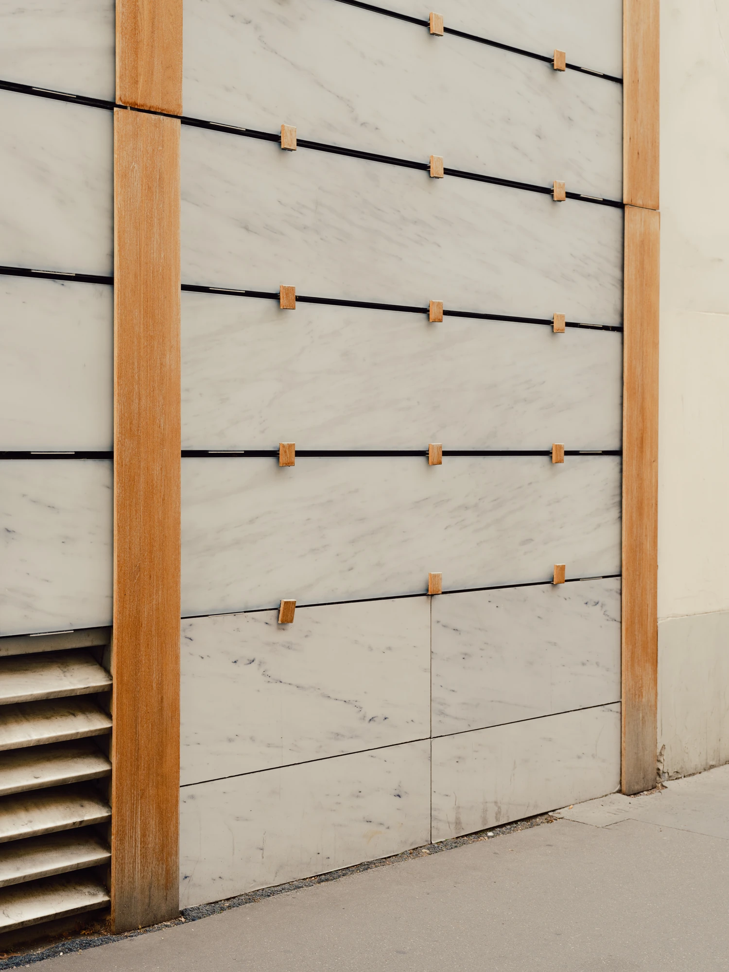 Église Saint-François de Molitor by Corinne Callies and Jean-Marie Duthilleul — A detail of the marble rainscreen, veined white panels carried on black horizontal rails and held off the wall by small timber blocks.