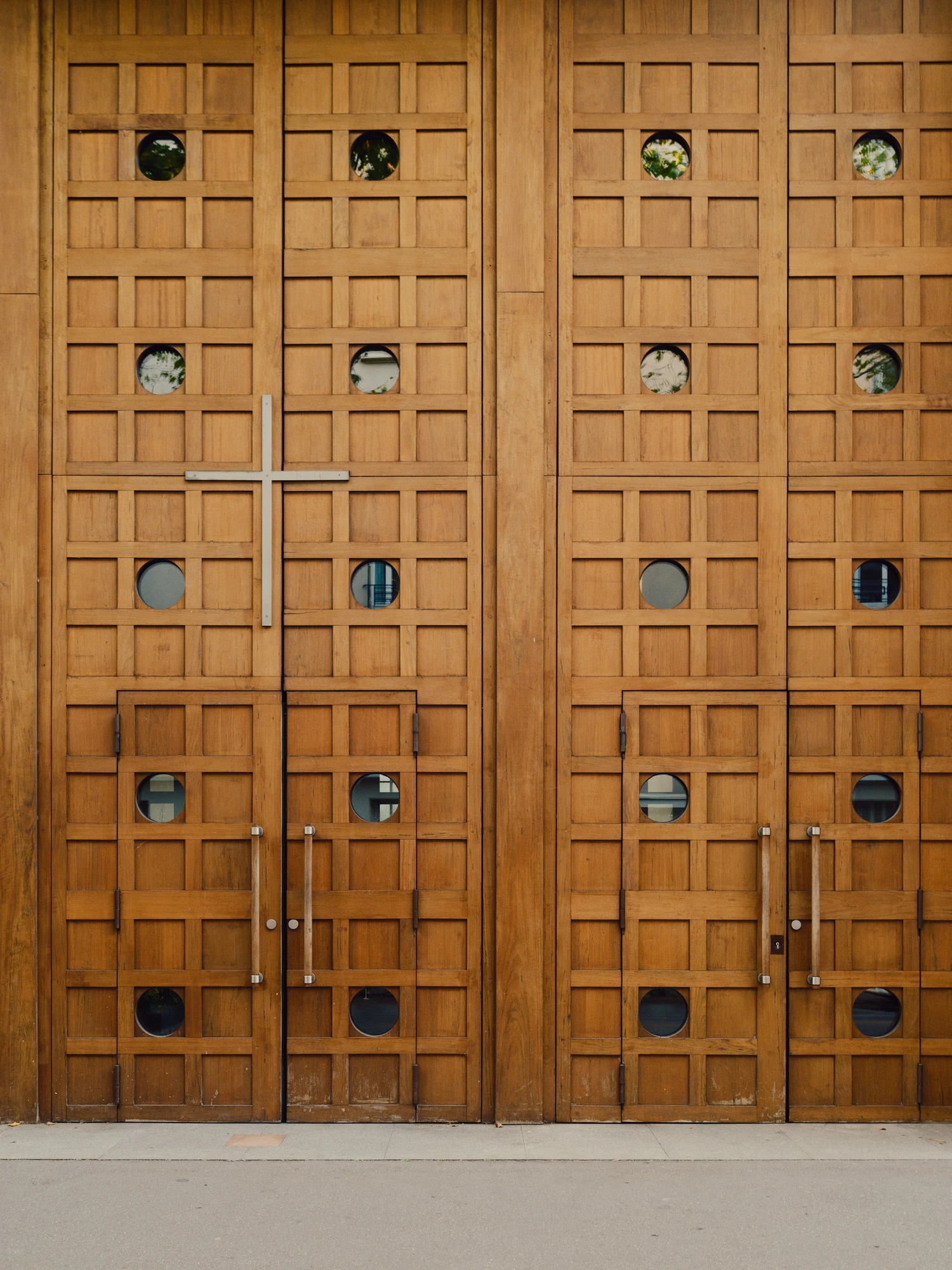 Église Saint-François de Molitor by Corinne Callies and Jean-Marie Duthilleul — The entrance doors at close range, their timber faces divided into a grid of square panels set with circular glazed cabochons.