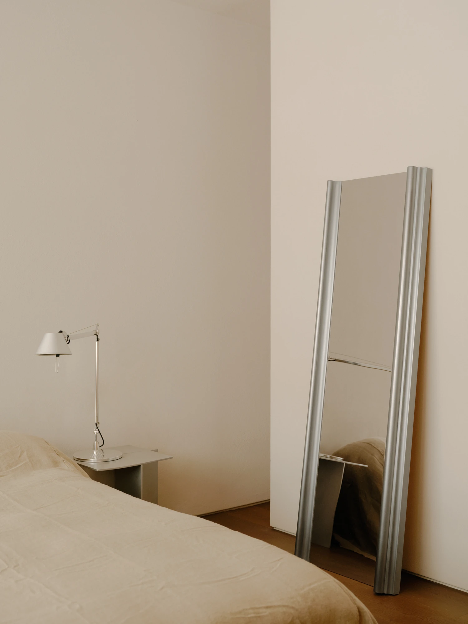 49 Walsh Street by MORQ, photographed by Tom Ross — A bedroom corner in pale render, with a full-length mirror in a ribbed aluminium frame leaning against the wall.