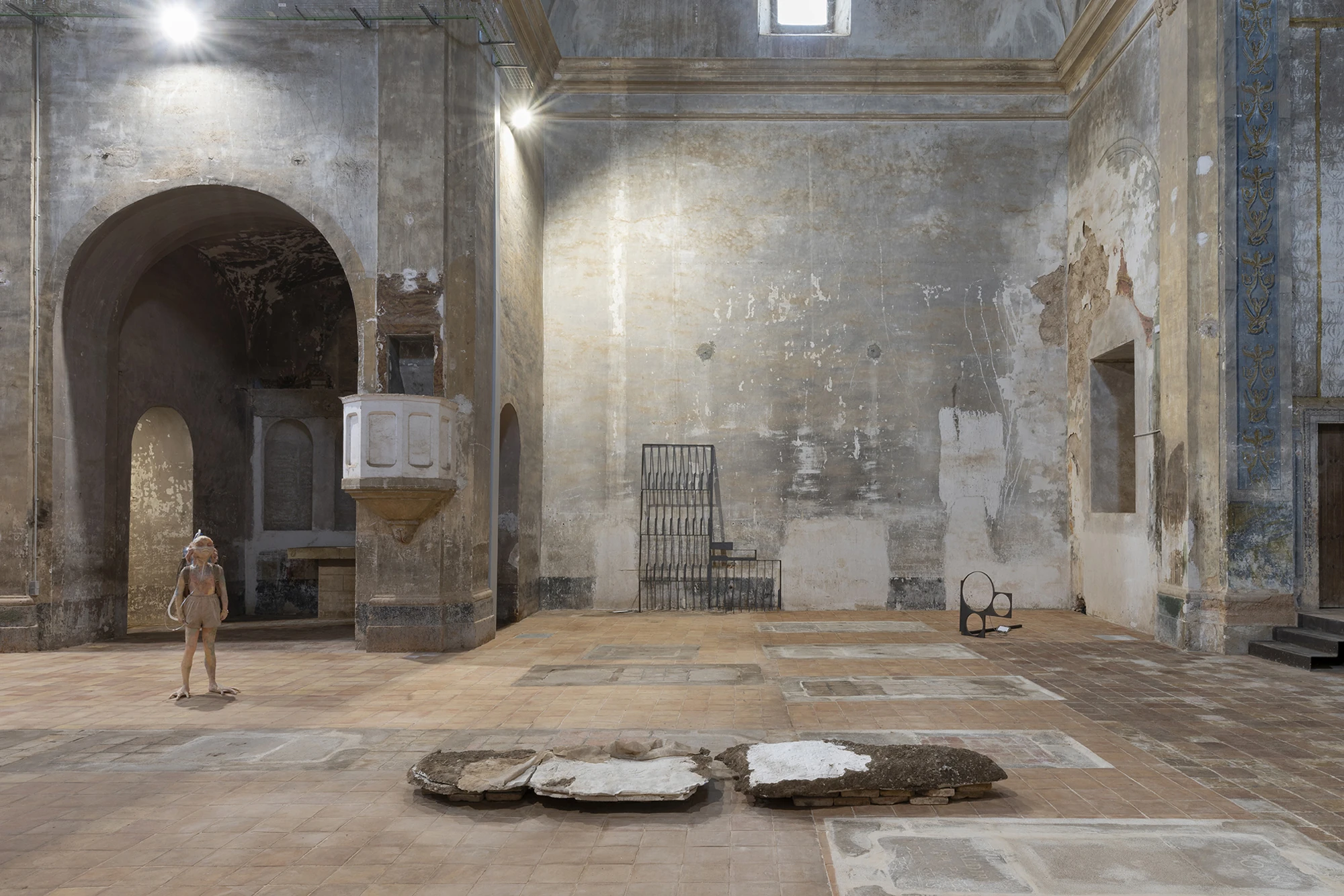 KIN TOO by Spiritvessel, photographed by Roberto Ruiz — Wide view of KIN TOO: Michele Gabriele's figure at left, Jordi Mitjà's steel grille and circular form along the wall, and Monia Ben Hamouda's plaster slabs across the floor.