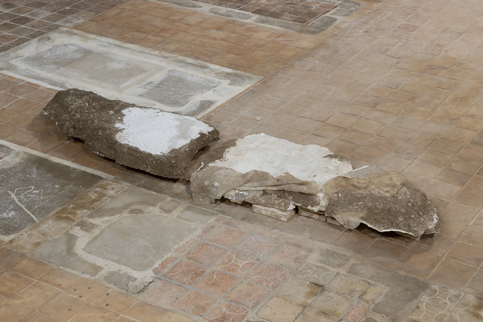 KIN TOO by Spiritvessel, photographed by Roberto Ruiz — Two slabs of Monia Ben Hamouda's Ghost series, white plaster caked with earth, resting over the worn grave markers of the church floor.