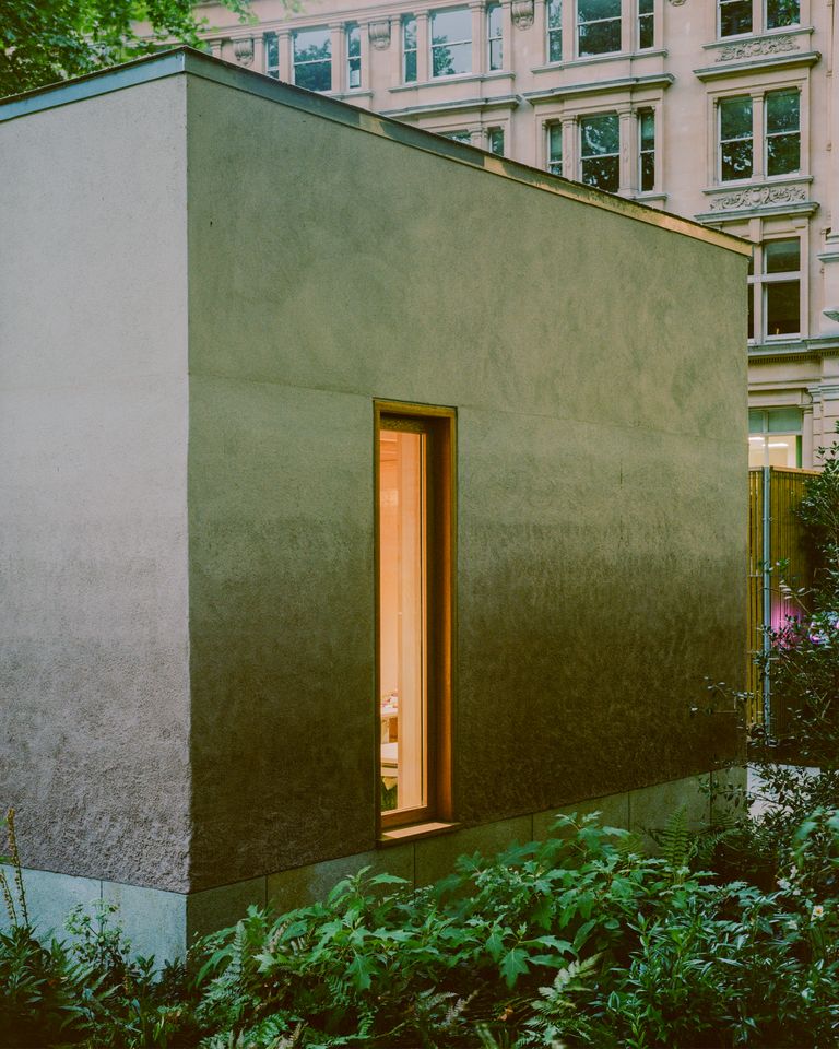 Finsbury Circus Parks Office by Studio Weave, photographed by Lorenzo Zandri — A single slot window glows against clay render above a base of Kentish Ragstone, framed by low garden planting.