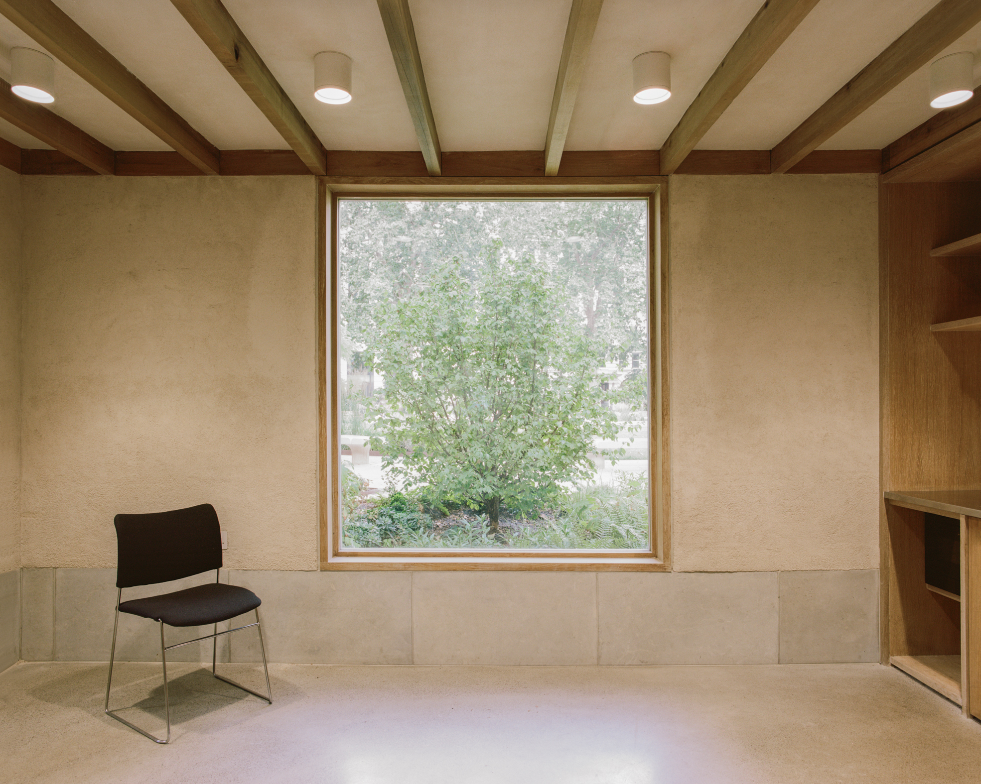 Finsbury Circus Parks Office by Studio Weave, photographed by Lorenzo Zandri — In the sitting room, a large square window frames a young tree beside built-in oak joinery and a timber-beamed ceiling.