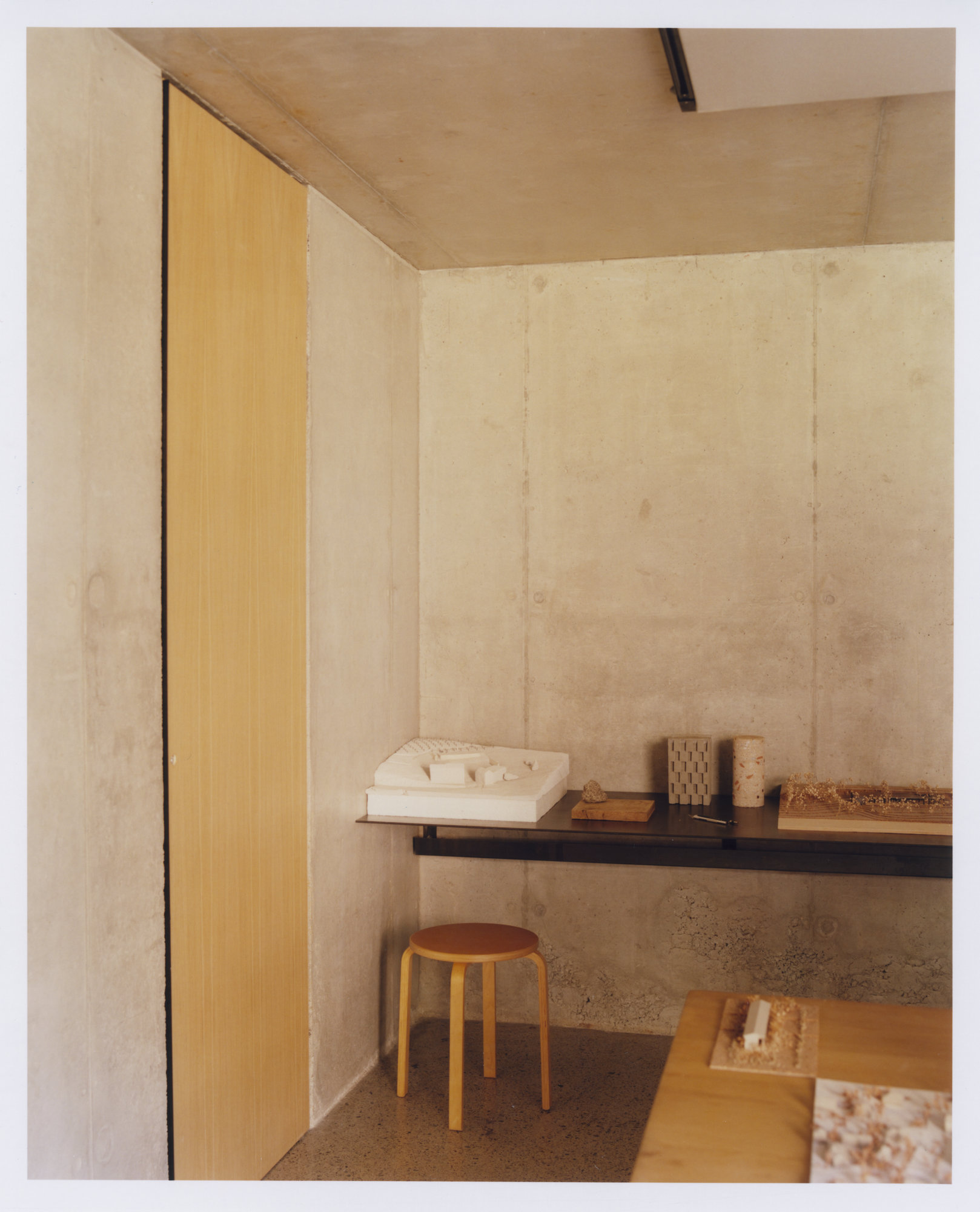 Office Orma Architettura by Orma Architettura — The stone office at dusk among the roofs of the hamlet, forested mountains rising behind.
