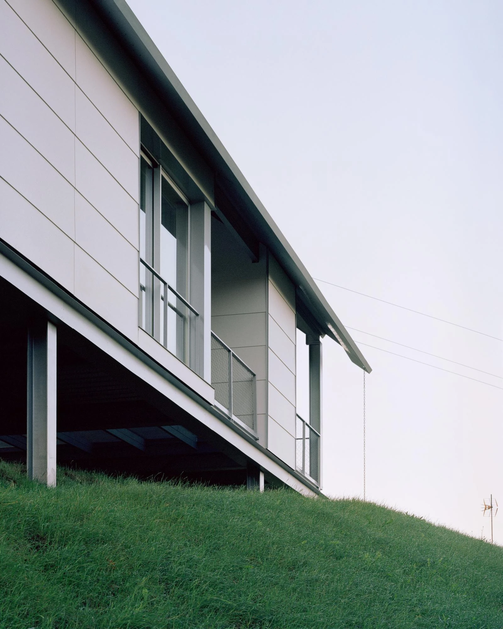 Casa Guadalupe by HANGHAR, photographed by Rory Gardiner — A low view of the underside, where galvanized steel columns and beams carry the house above the hill.