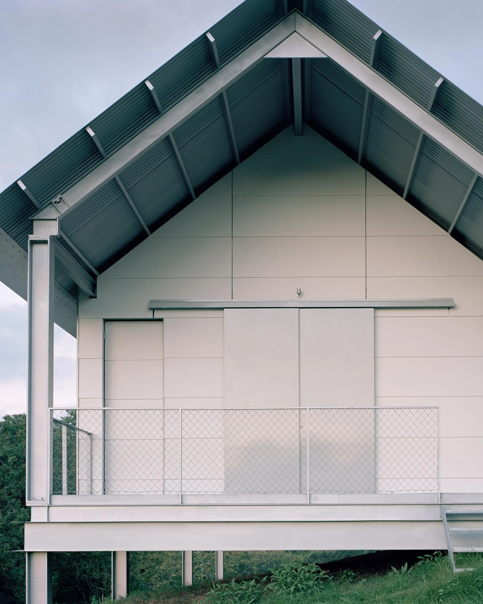Casa Guadalupe by HANGHAR, photographed by Rory Gardiner — The symmetrical gable end, its pitched corrugated roof carried on exposed steel rafters.