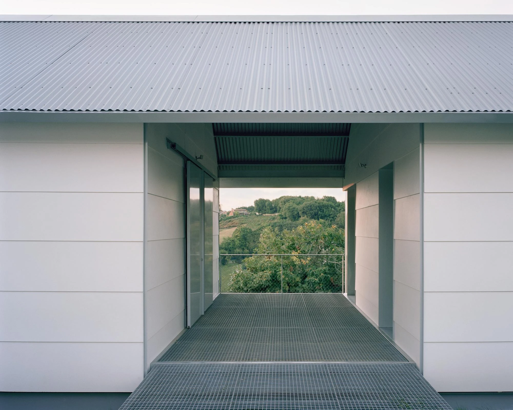 Casa Guadalupe by HANGHAR, photographed by Rory Gardiner — The frontal porch opening under a corrugated eave, floored in galvanized grating.