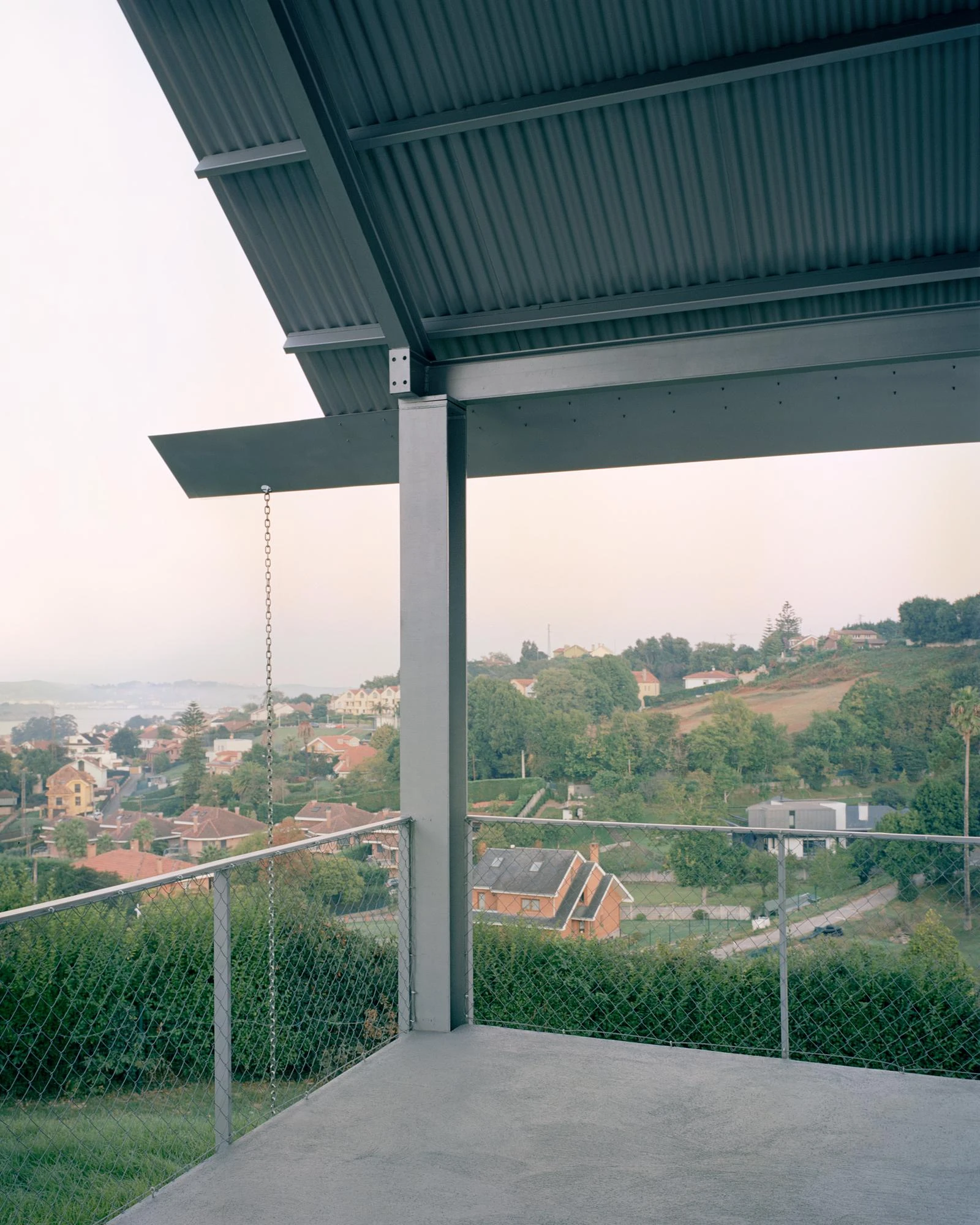 Casa Guadalupe by HANGHAR, photographed by Rory Gardiner — The deep eave's corrugated soffit meets a steel column, a downpipe chain hanging alongside.