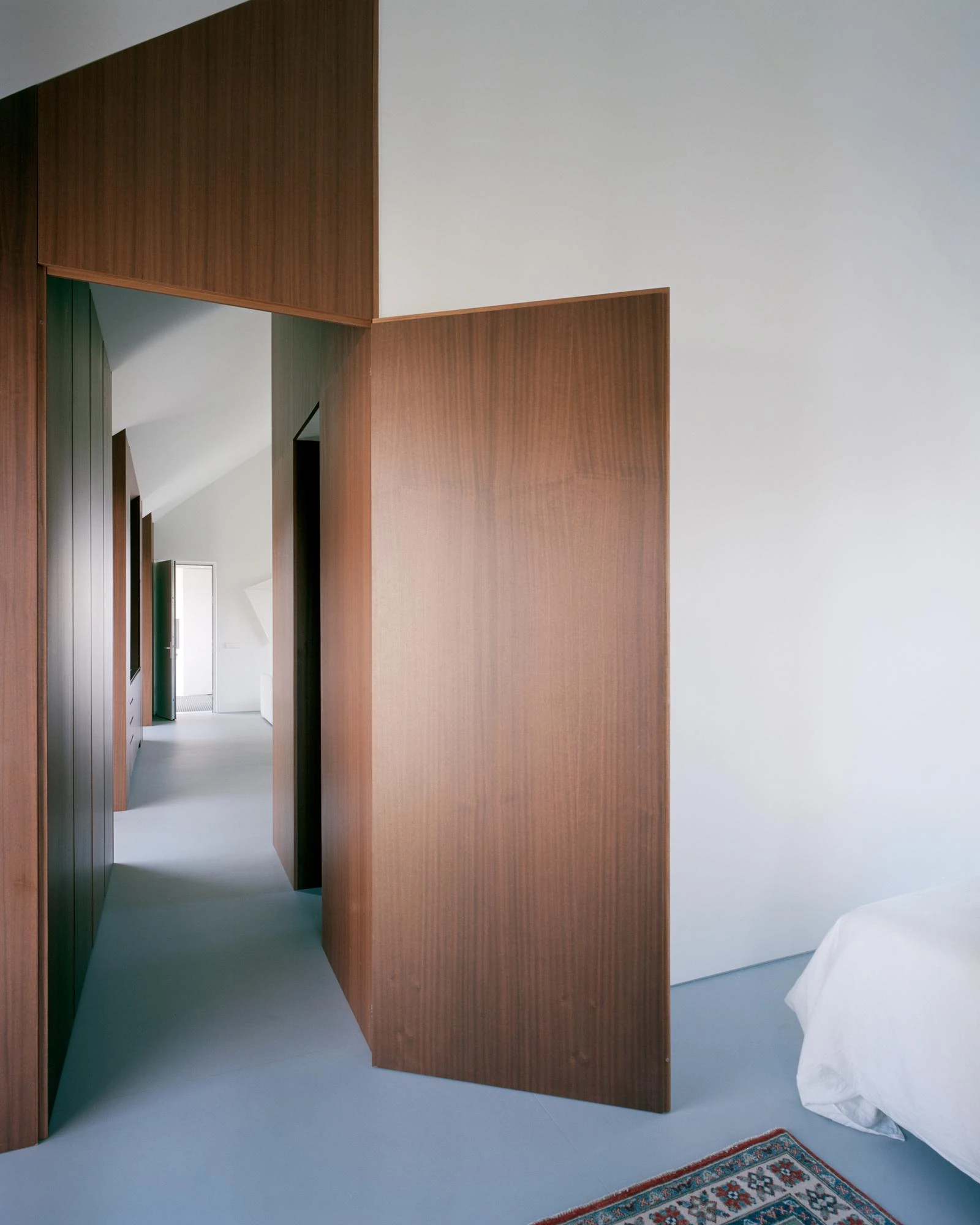 Casa Guadalupe by HANGHAR, photographed by Rory Gardiner — A pivoting sapele volume screens the bedroom, standing on a pale blue-grey resin floor.