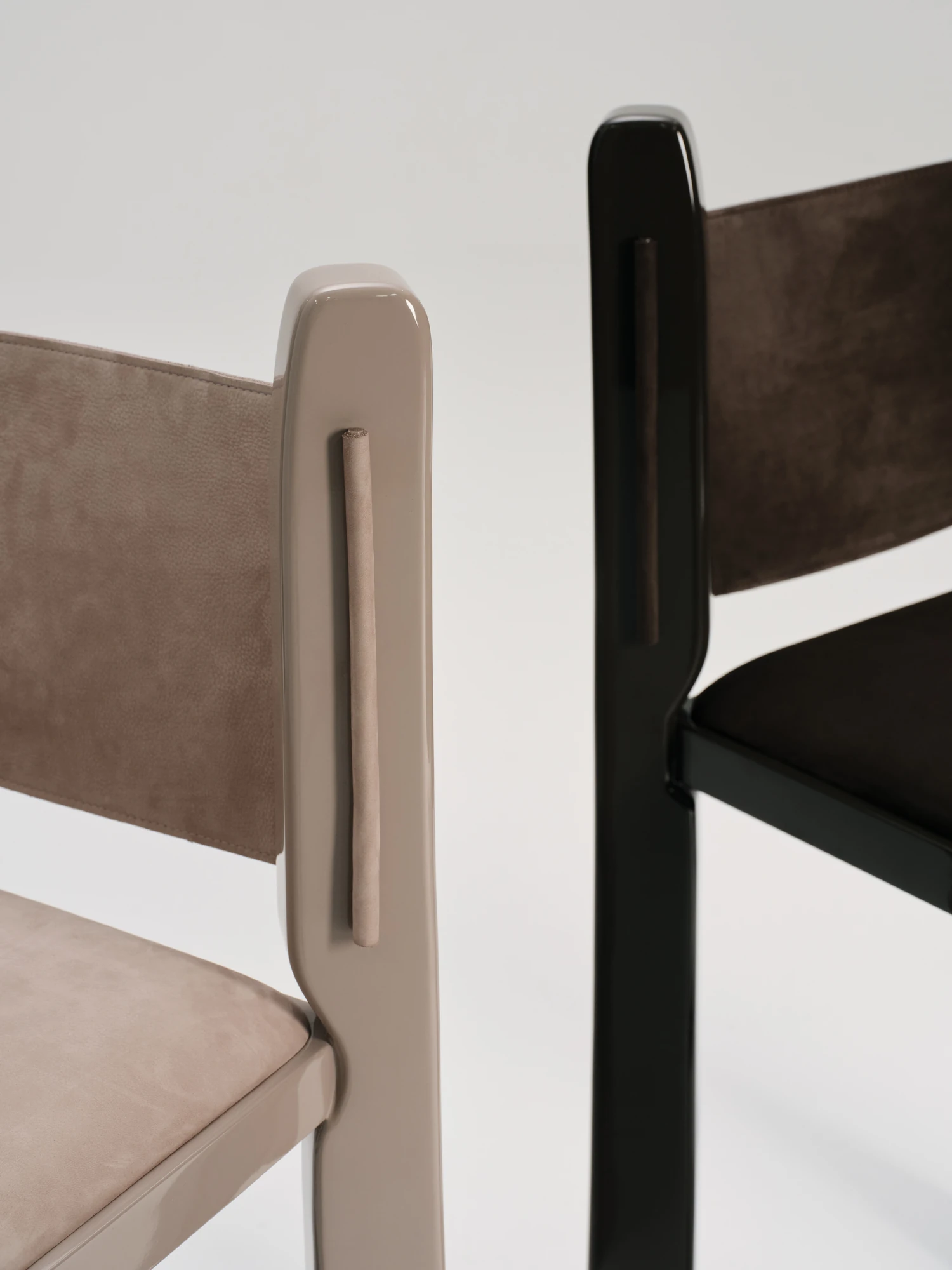 Ruby by NOVSEP, photographed by NOVSEP — Close detail of two Ruby frames in greige and black gloss lacquer, revealing the leather-wrapped cord set into each stile beside a suede sling.