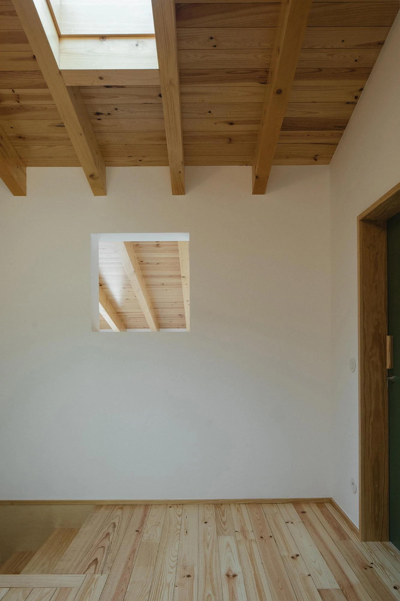 House in Cerrado by Atelier Espaço P2, photographed by José Campos — A bedroom of pine ceiling and pine floor is pierced by a small square internal window that borrows light from the room beyond.