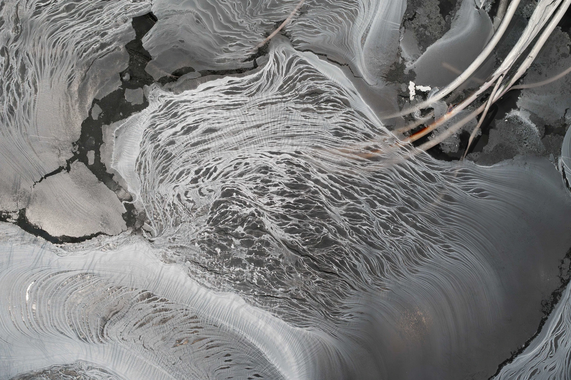 Accomplice by Yein Lee, photographed by Blaž Gutman / MGML — Close view of the pool surface in Accomplice, an abstract field of grey and white swirled sediment crossed by thin lines.
