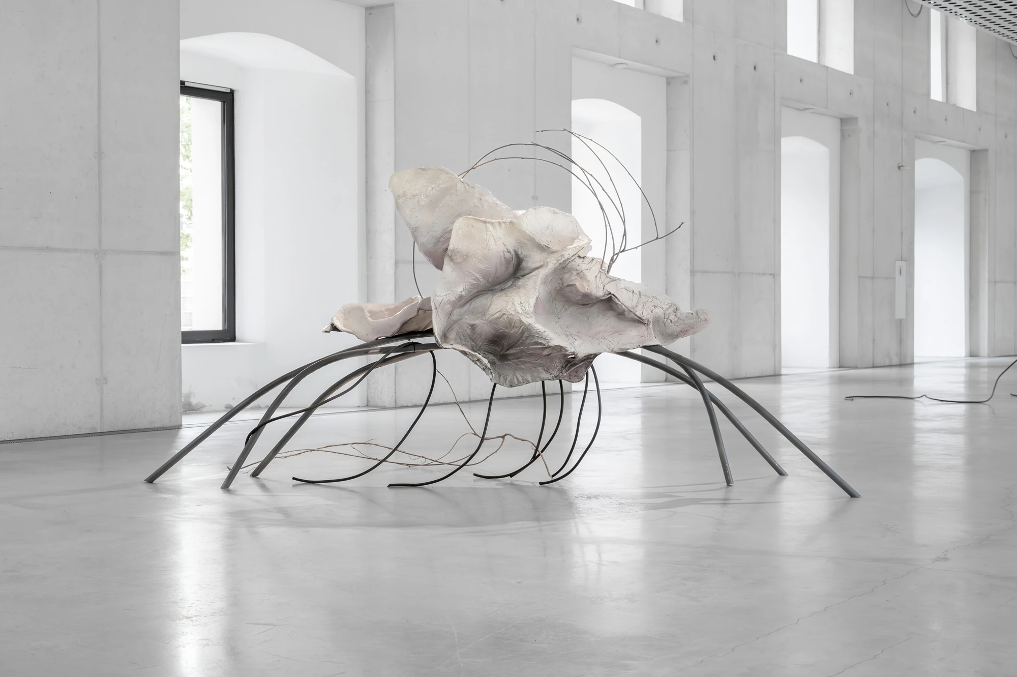 Accomplice by Yein Lee, photographed by Blaž Gutman / MGML — A single sculpture of pale bloom-like cast forms resting on arched metal legs in the bright, near-empty Parterre Gallery.