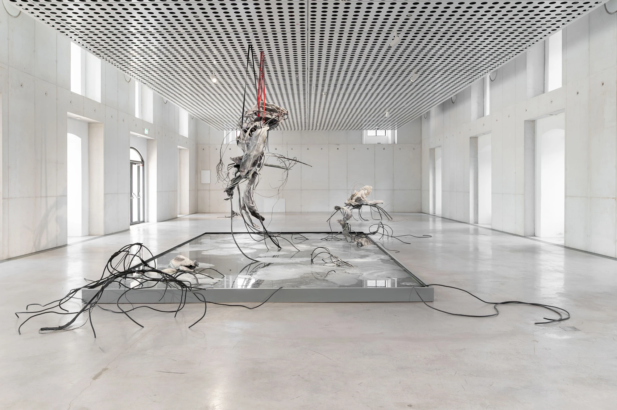 Accomplice by Yein Lee, photographed by Blaž Gutman / MGML — Frontal installation view of Accomplice, the central suspended sculpture over the pool with daylight and greenery through the far doors.