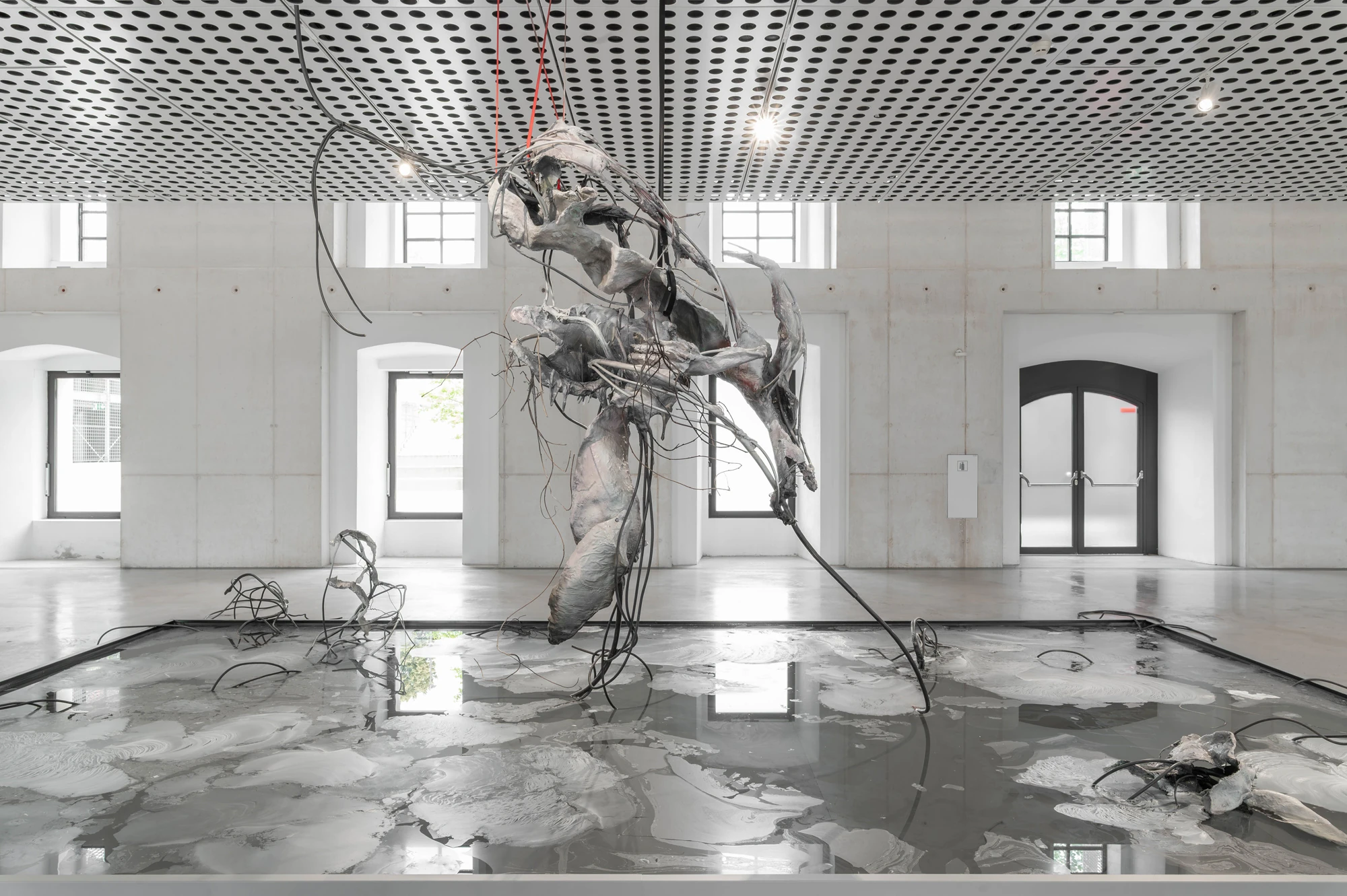 Accomplice by Yein Lee, photographed by Blaž Gutman / MGML — Installation view of the suspended central sculpture above the pool, windows and greenery behind it in the Parterre Gallery.