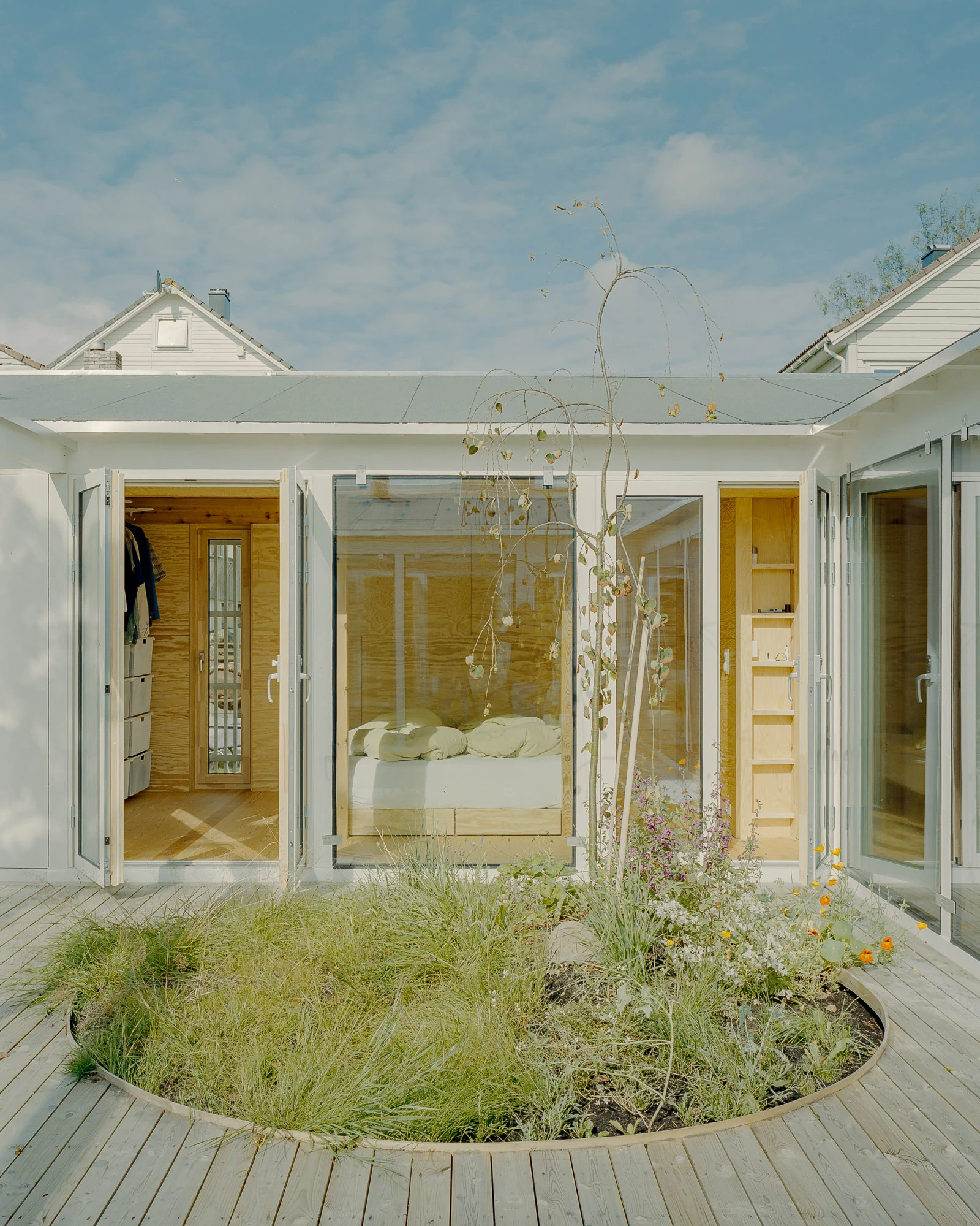 Ersland & Skeie House by Knut Hjeltnes Architects, photographed by Hugo Lütcherath — The main living space in pine and peeled pine plywood, with a black wood-burning stove and built-in shelving.