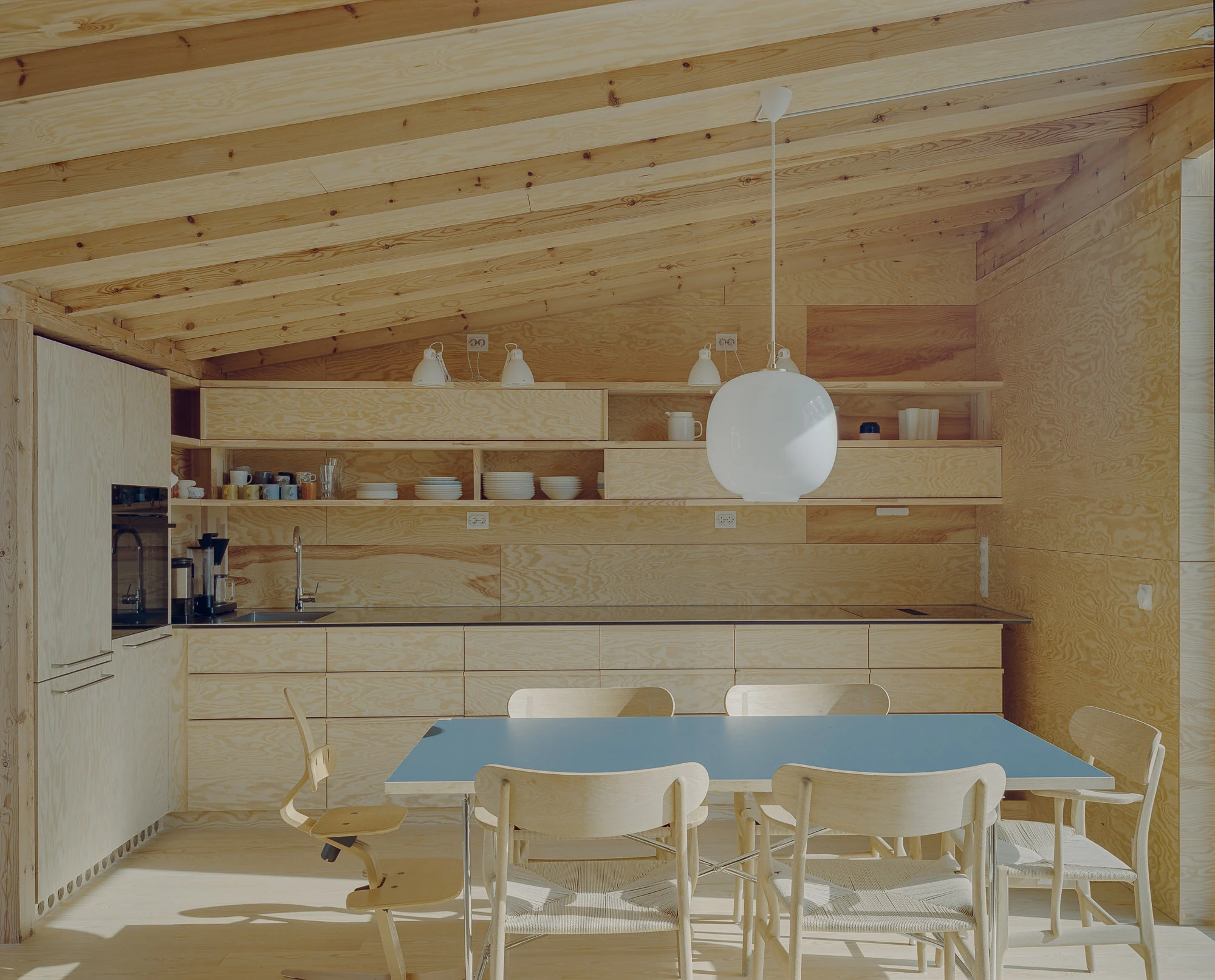 Ersland & Skeie House by Knut Hjeltnes Architects, photographed by Hugo Lütcherath — The kitchen is built entirely of pine and peeled pine plywood, its bespoke units set beneath a low beamed soffit.