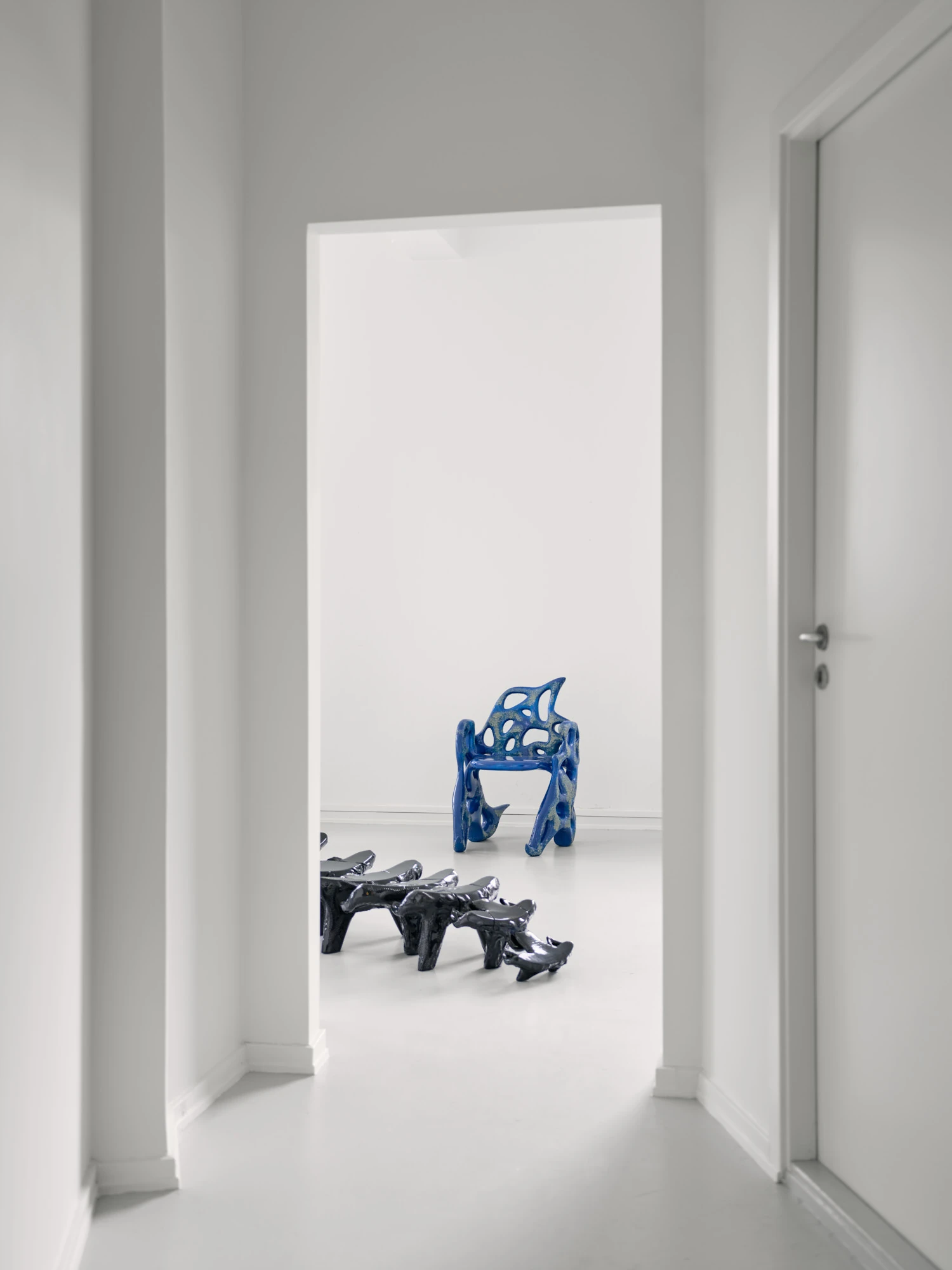 Extrude, Bridge, Fill by Lasse Sylvest Lilleør, photographed by Robert Damisch — Installation view through a doorway, the cobalt Sleigh Chair beyond and the Dazing Devil lounger in the foreground.
