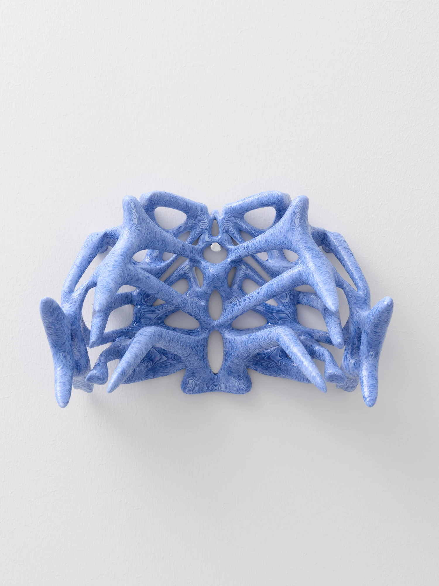 Extrude, Bridge, Fill by Lasse Sylvest Lilleør, photographed by Robert Damisch — A radiated rib vase mounted on the wall, its bone-blue arms spreading from a central web, printed in PLA, resin and dye.