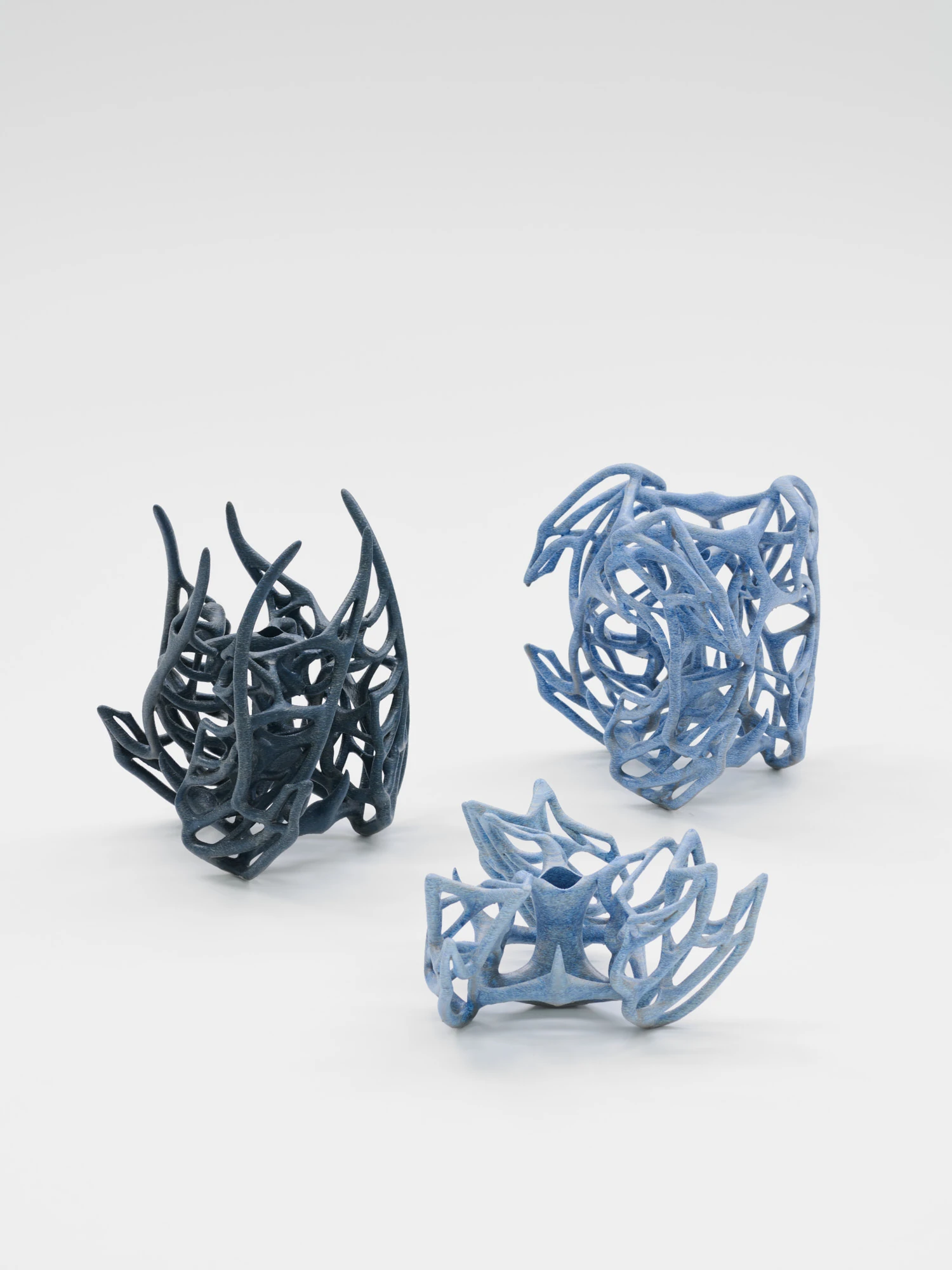Extrude, Bridge, Fill by Lasse Sylvest Lilleør, photographed by Robert Damisch — Three radiated rib vases grouped together, from navy to pale blue, each an open thicket of printed ribs.