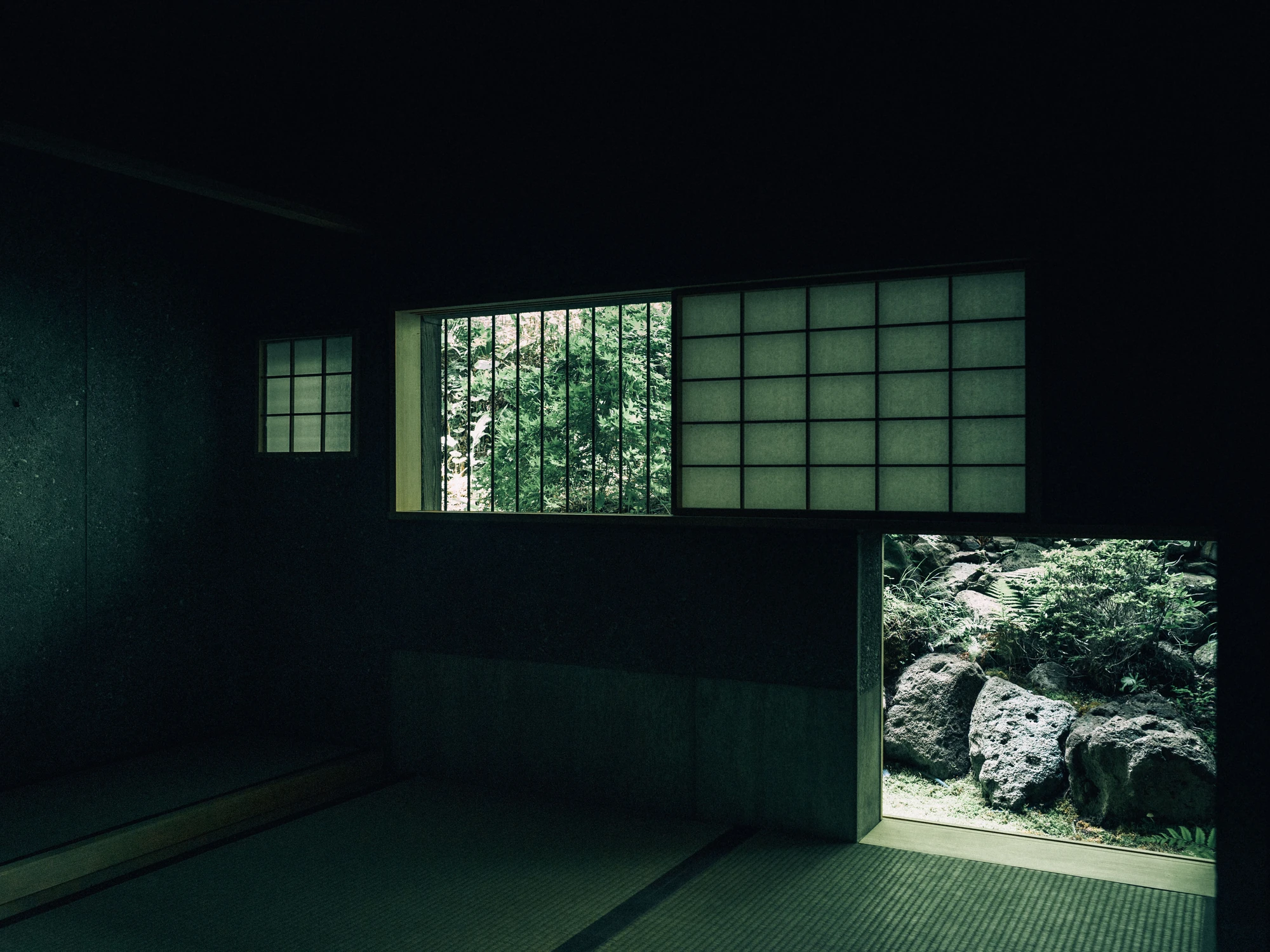 Konkuri-an by Teitakusubako, Yusuke Igarashi Architects, photographed by Kentaro Nemoto, Kazumasa Harada — Paper screens and a low garden opening puncture the dark concrete wall, framing rock and planting from the valley.
