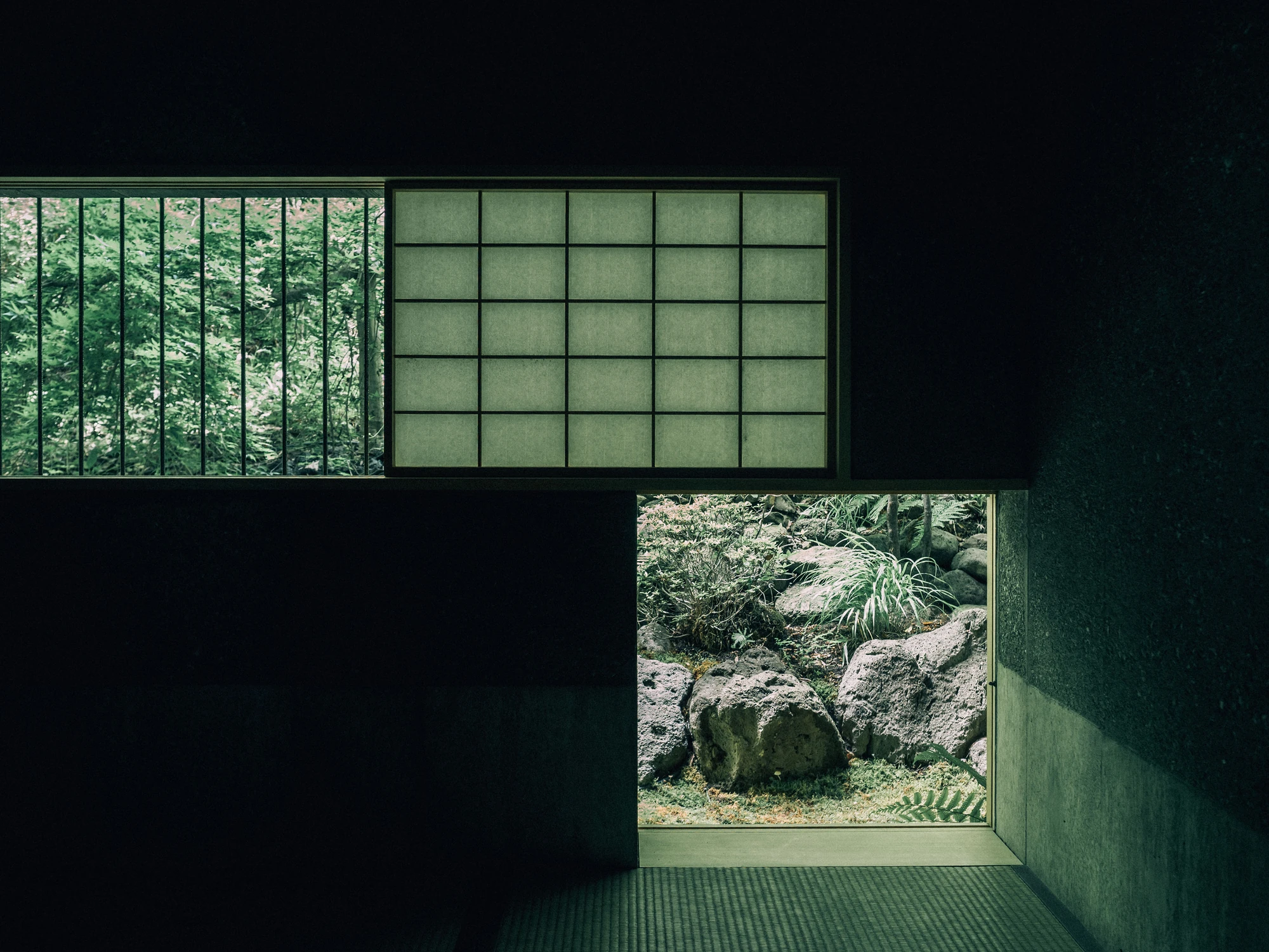 Konkuri-an by Teitakusubako, Yusuke Igarashi Architects, photographed by Kentaro Nemoto, Kazumasa Harada — Paper screens above a floor-level opening cut through the concrete wall to rock and fern outside.